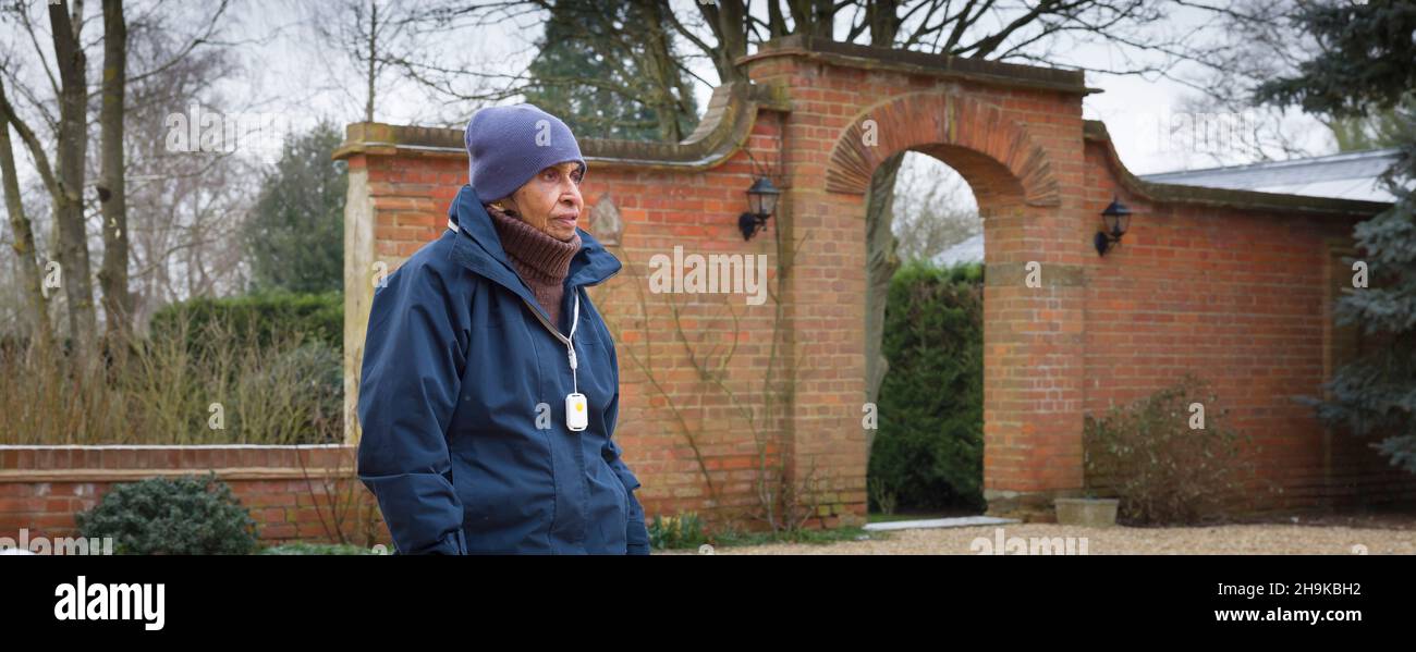 Alte, ältere Asiaten. Ältere Inderin mit 80s Jahren, die bei britischem Winterwetter draußen ging. Tragen eines persönlichen Sicherheitsalarms Stockfoto