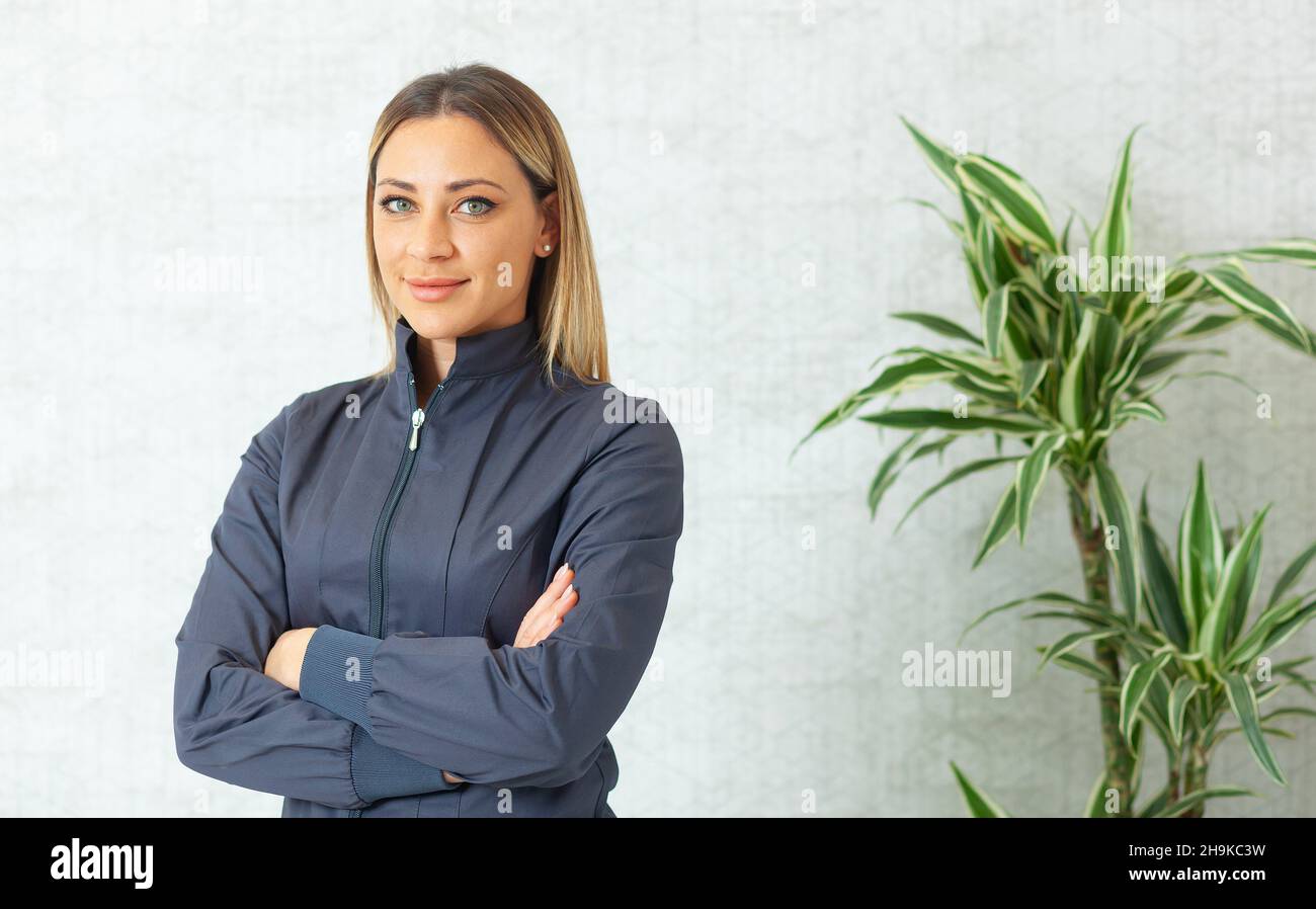 Porträt einer schönen lächelnden Frau mit blonden Haaren und grünen Augen. Sie trägt professionelle medizinische Kleidung, die für den Einsatz in der Medizin, Dextrist vorstellbar ist Stockfoto