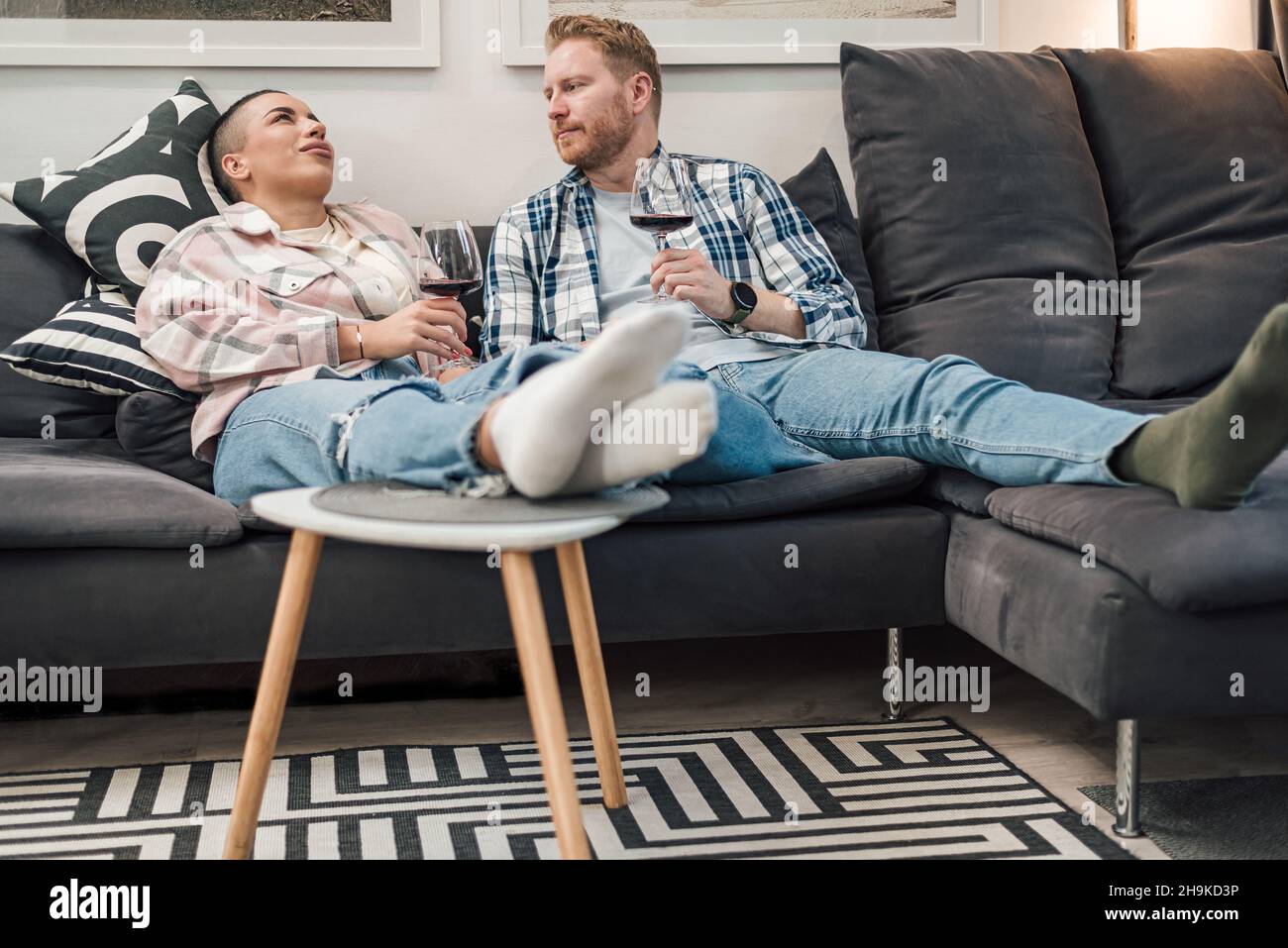 Junge Erwachsene Personen Paar in Beziehung genießen sich und haben eine tolle Zeit zu Hause zwanglose Atmosphäre Wein trinken entspannt auf Sofa A sitzen Stockfoto