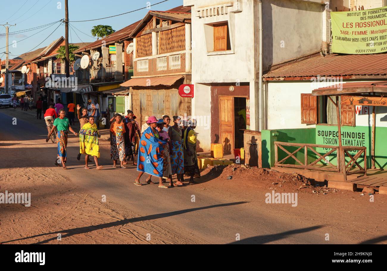 Ihosy, Madagaskar - 05. Mai 2019: Eine Gruppe von unbekannten madagassischen Frauen und Männern in hellen Kleidern, die auf der Stadtstraße spazieren, die Nachmittagssonne scheint ihnen. Typi Stockfoto