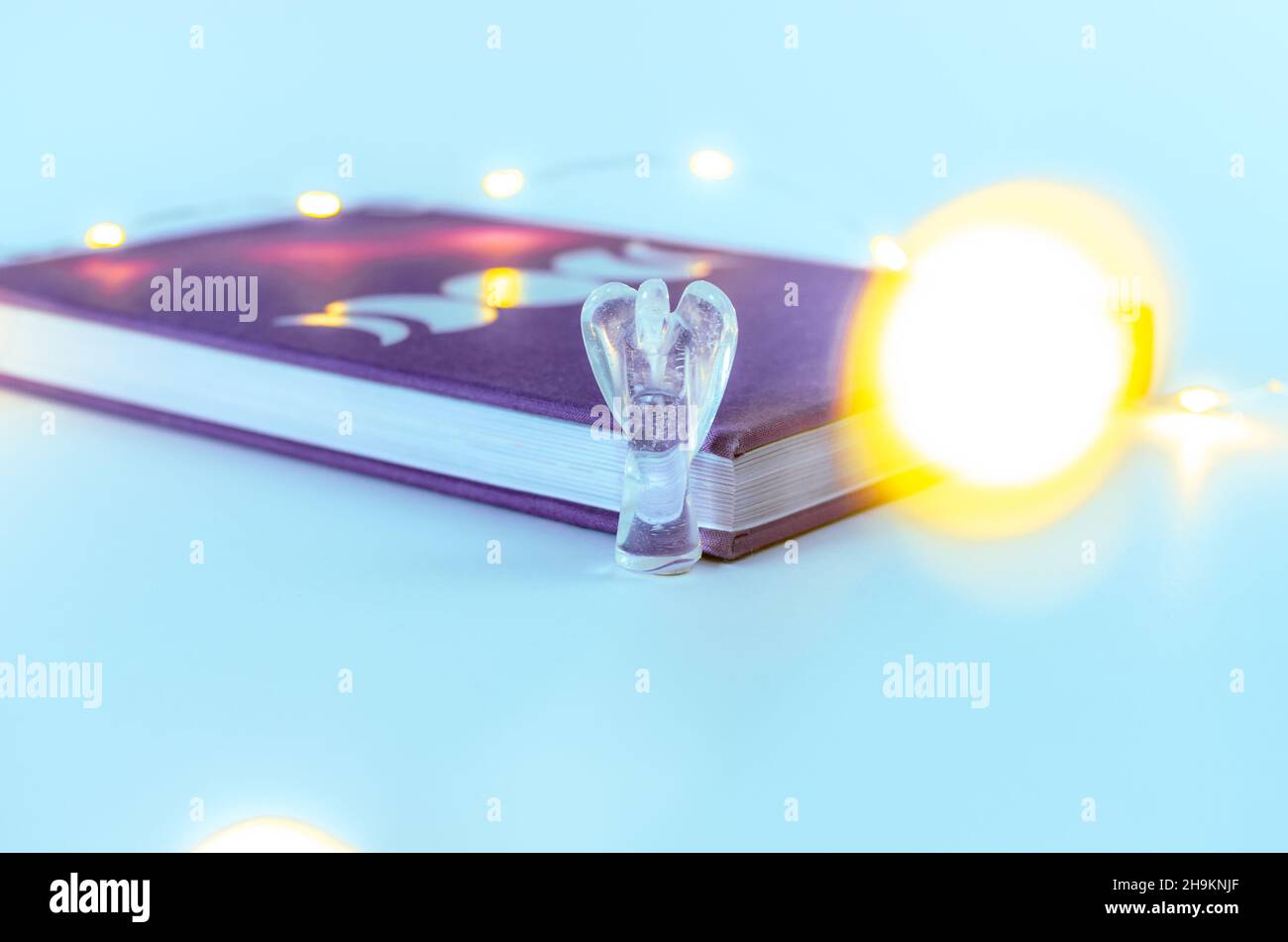 Nahaufnahme von Engelskristall aus klarem Quarz in der Nähe eines Mondjournals mit Weihnachtslichtern und Weihrauch auf dem Hintergrund. Konzept: Spirituelle Selbstversorger-Praktiken Stockfoto