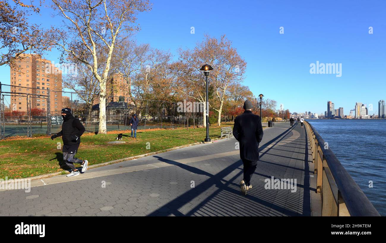 Jogger und Menschen auf der East River Waterfront Esplanade im East River Park in der Lower East Side von Manhattan, New York, NY. 23. November 2021. Stockfoto