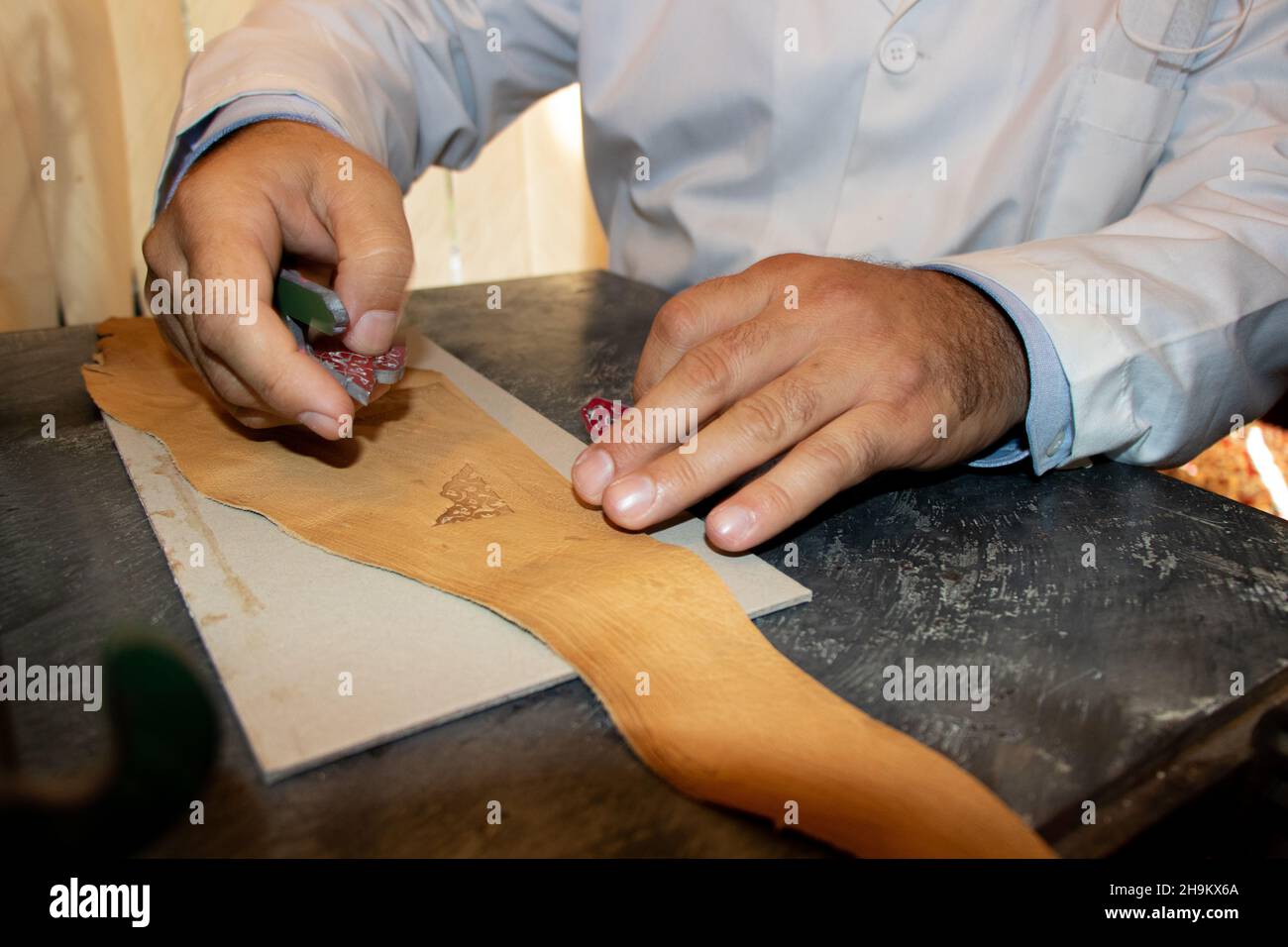 Nahaufnahme eines Lederhandlers, der mit Leder arbeitet. Herstellung von handgefertigten Lederwaren. Lederwerkstatt. Stockfoto