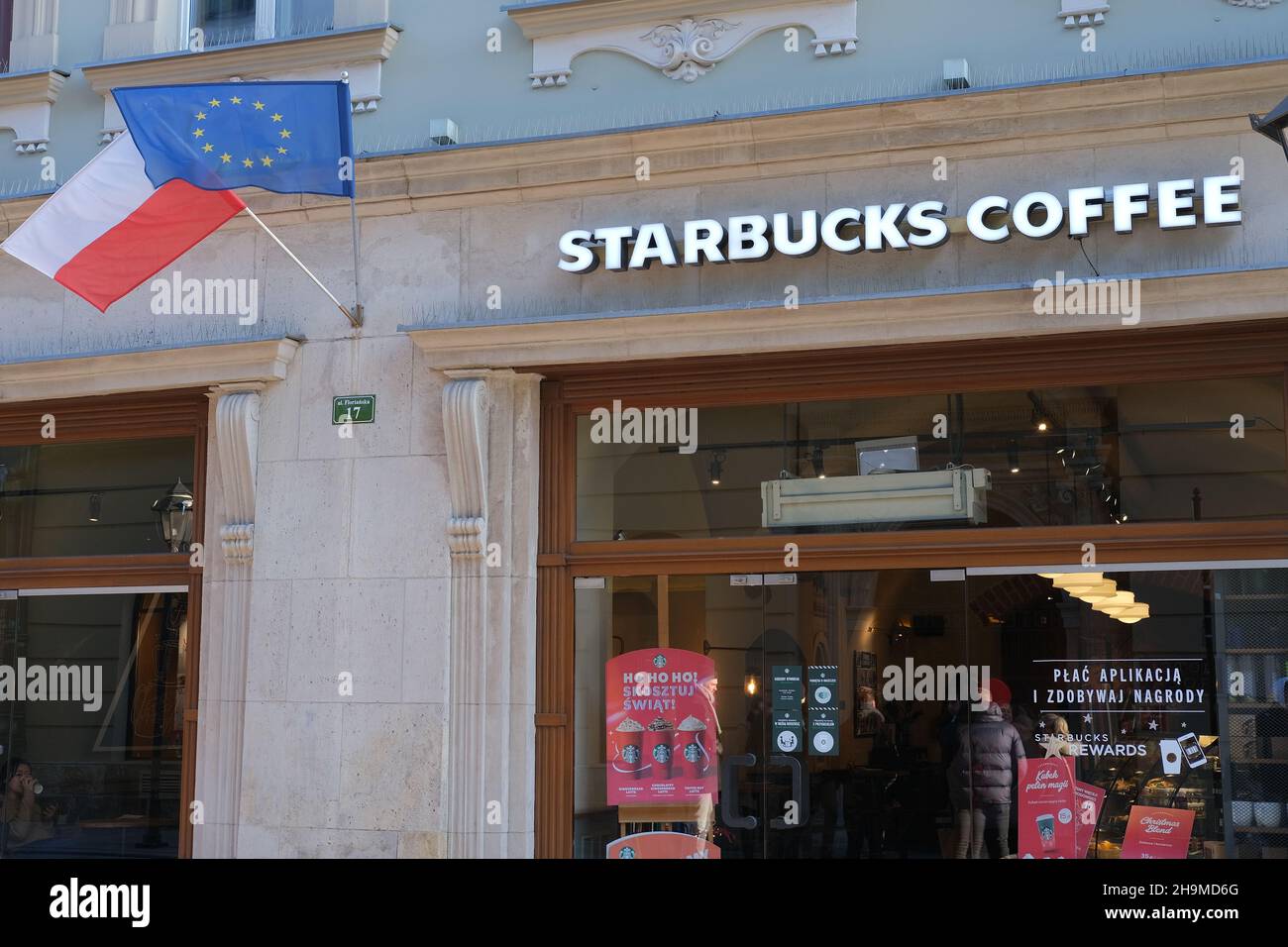 KRAKAU, POLEN - 2. DEZEMBER 2021: Eingang zum Starbucks Coffee Shop. Starbucks-Kaffee in Krakau Polen, Menschen, die in Starbucks kommen, Menschen trinken Kaffee Stockfoto