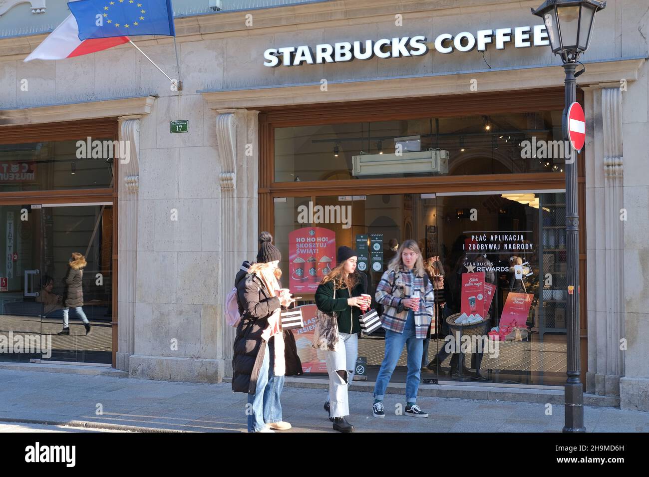 KRAKAU, POLEN - 2. DEZEMBER 2021: Eingang zum Starbucks Coffee Shop. Starbucks-Kaffee in Krakau Polen, Menschen, die in Starbucks kommen, Menschen trinken Kaffee Stockfoto