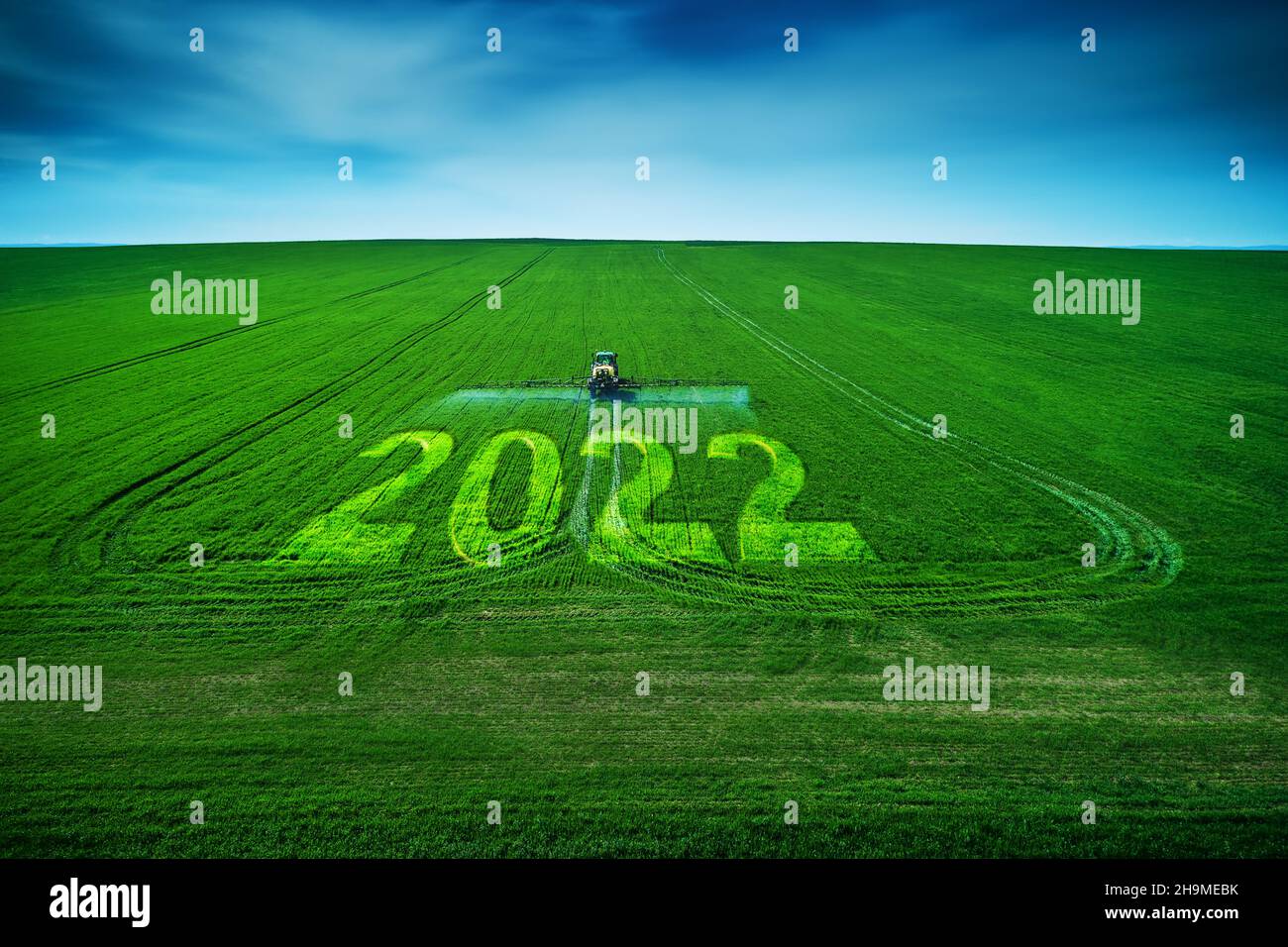 2022 Happy New Year Konzept und Luftaufnahme des landwirtschaftlichen Traktors Pflügen und Spritzen auf dem Feld. Stockfoto