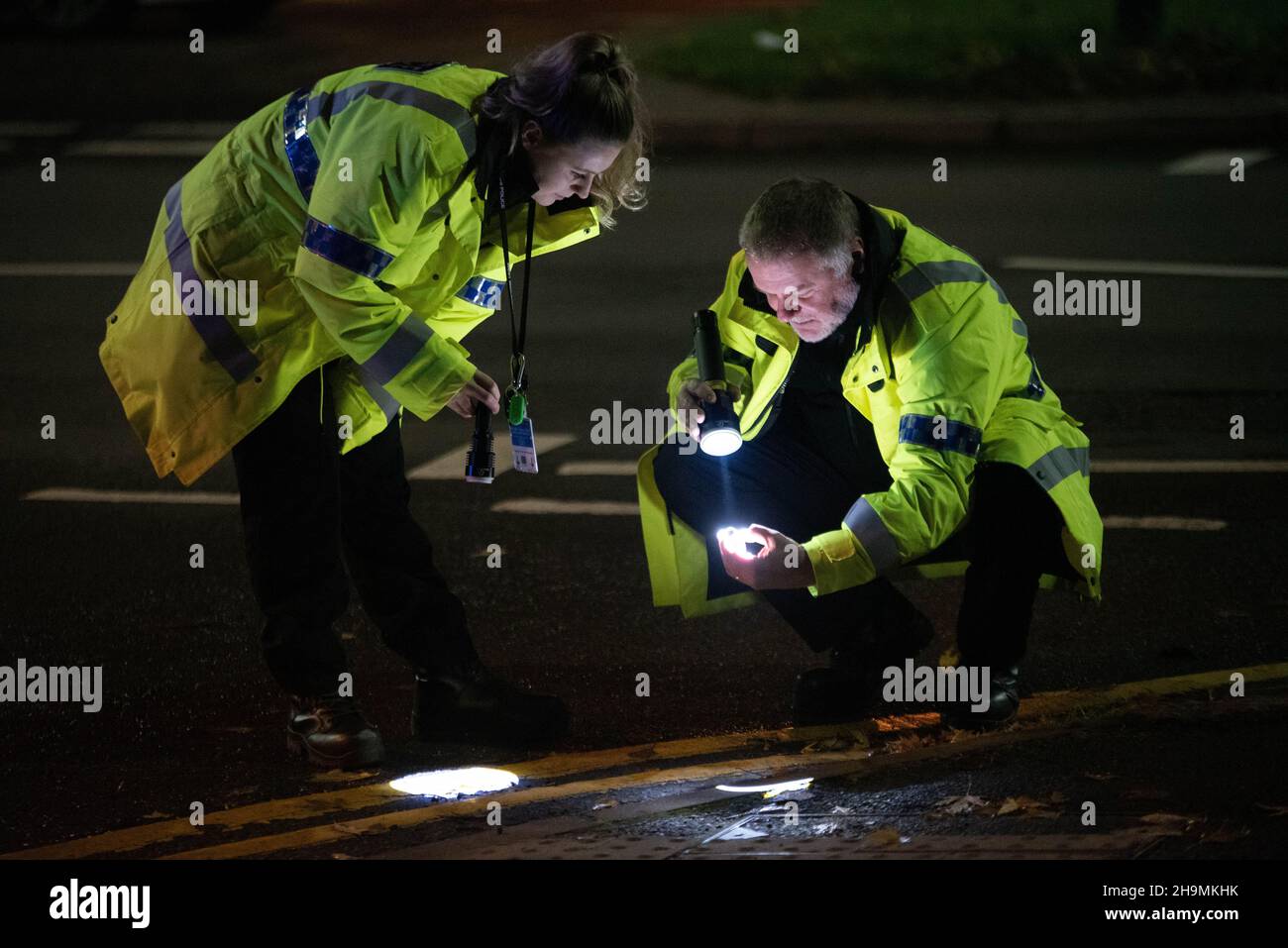 Forensische Kollisionsermittler der West Midlands Police, Erdington, Birmingham, untersuchen Beweise am Tatort eines Treffers und einer Flucht Stockfoto