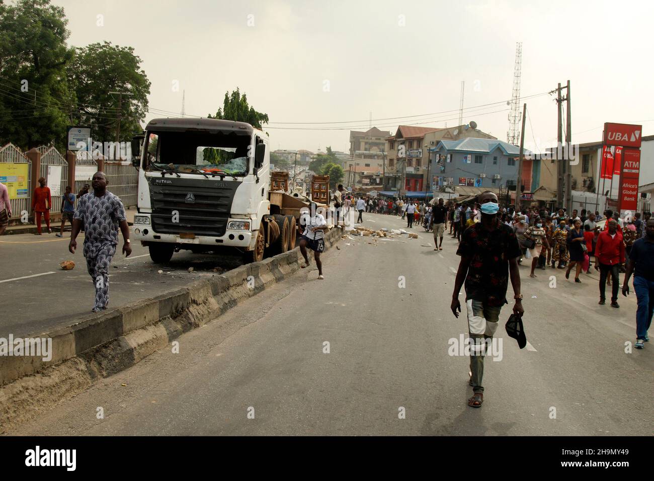 Lagos, Nigeria, 7th. Dezember 2021. Passanten kommen an einem der Lastwagen vorbei, die von Protestierenden am Gymnasium in Ojodu, Lagos, Nigeria, verwüstet wurden, wo ein Lieferwagen, der angeblich von Verkehrsbeamten gejagt wurde, einige Studenten tötete, die von der Schule zurückkehrten. Während der Augenzeuge sagte, dass mindestens 17 Schüler starben, bestätigte die Polizei am Dienstag, dass drei Tote, 12 Verletzte, bei dem Unfall starben. Foto von Adekunle Ajayi Stockfoto