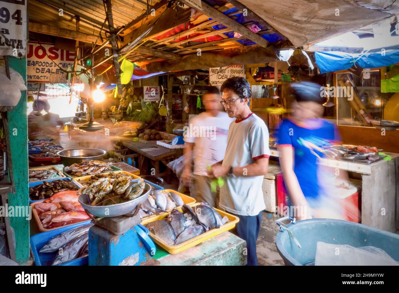 Puerto Galera, Philippinen - 6. Oktober 2013. Ein männlicher philippinischer Marktverkäufer, der frische Meeresfrüchte an seinem Stand in einem lokalen öffentlichen Frischmarkt verkauft. Stockfoto