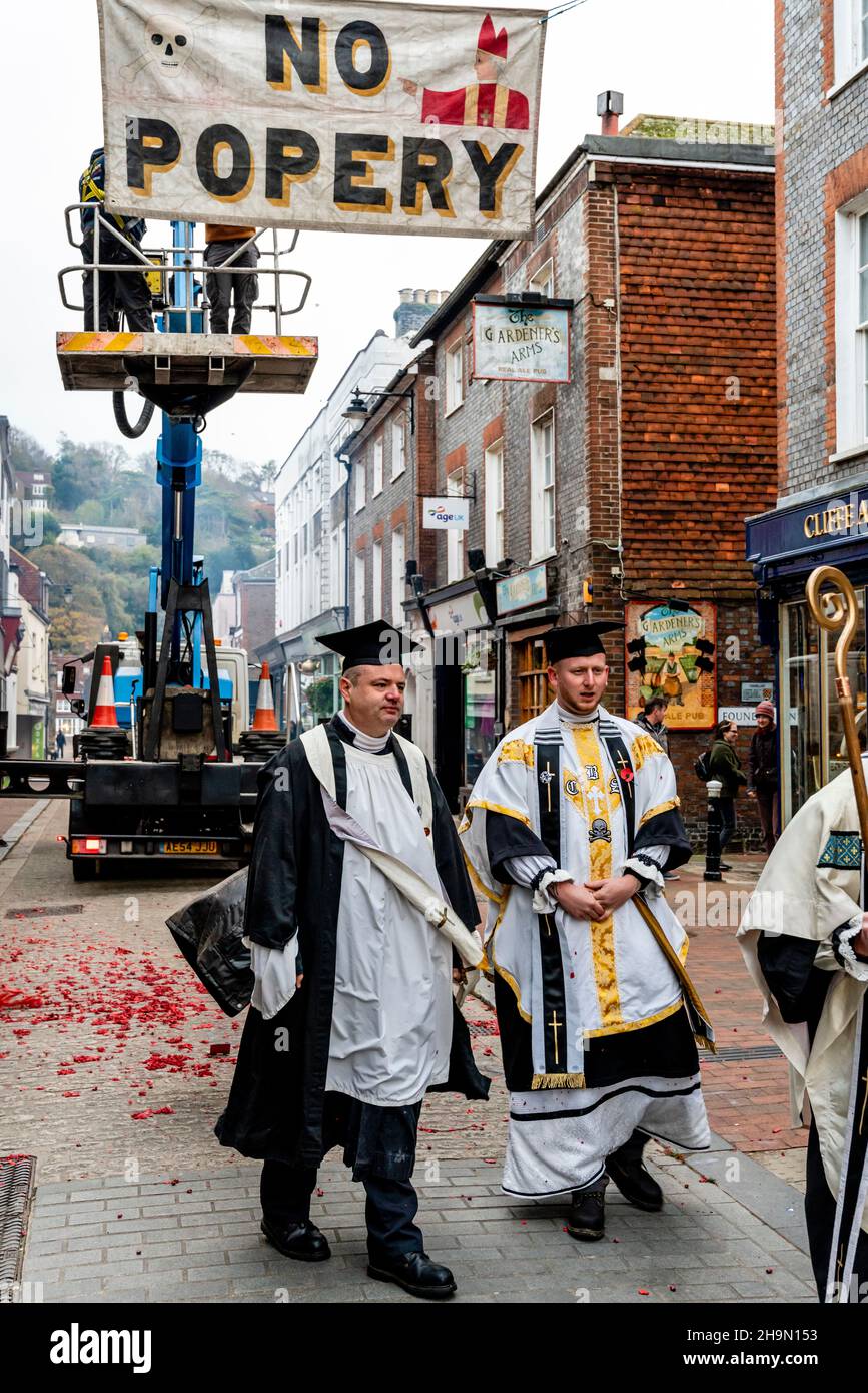 Mitglieder der Cliffe Bonfire Society in religiösem Kostüm Uhr als traditionelle Zeichen und Banner werden in den Straßen, Lewe, Sussex, Großbritannien, aufgesetzt. Stockfoto