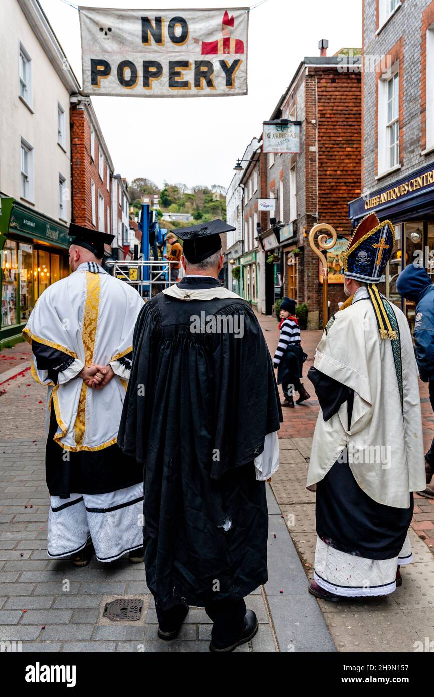 Mitglieder der Cliffe Bonfire Society in religiösem Kostüm Uhr als traditionelle Zeichen und Banner werden in den Straßen, Lewe, Sussex, Großbritannien, aufgesetzt. Stockfoto