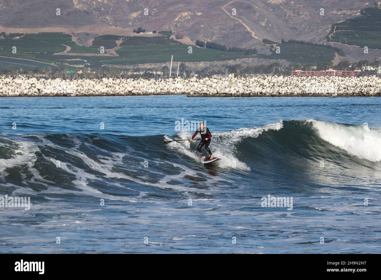 Stand Up and Paddle Boarder beim Wellenreiten am South Jetty Beach, Ventura Stockfoto