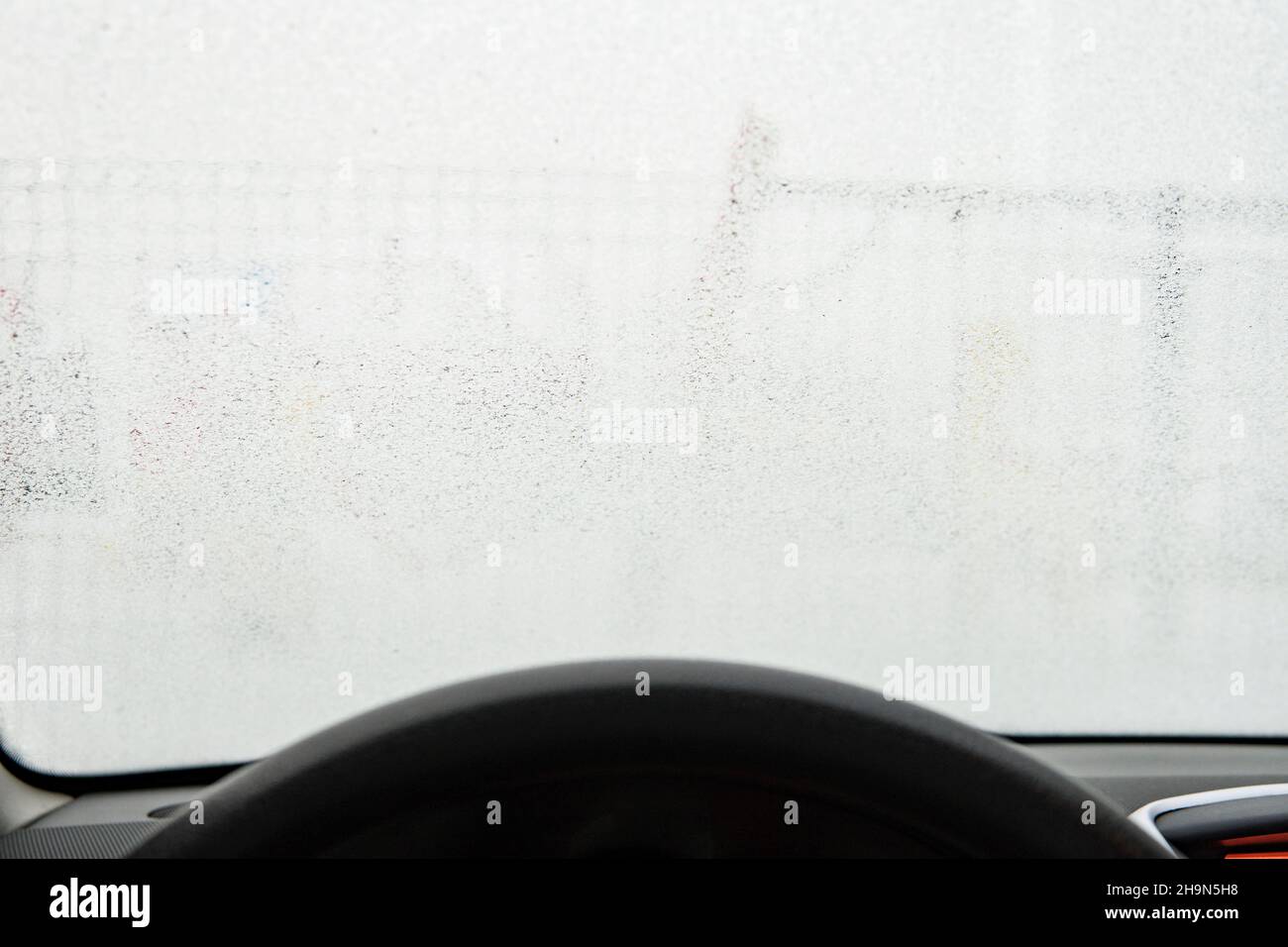 Frost an der Windschutzscheibe des Fahrzeugs. Blick von der Fahrerseite. Eine gefrorene Windschutzscheibe Stockfoto