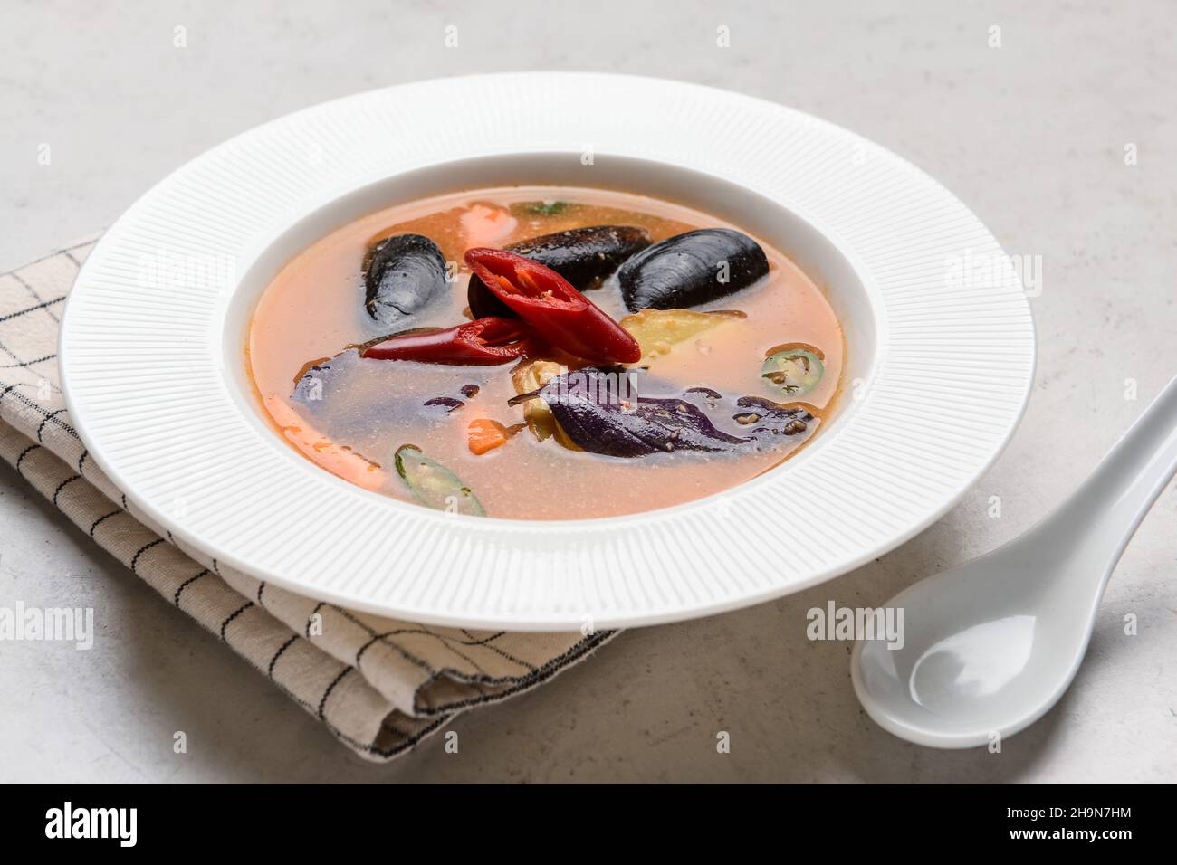 Schüssel mit würziger Thai-Suppe auf hellem Hintergrund Stockfoto