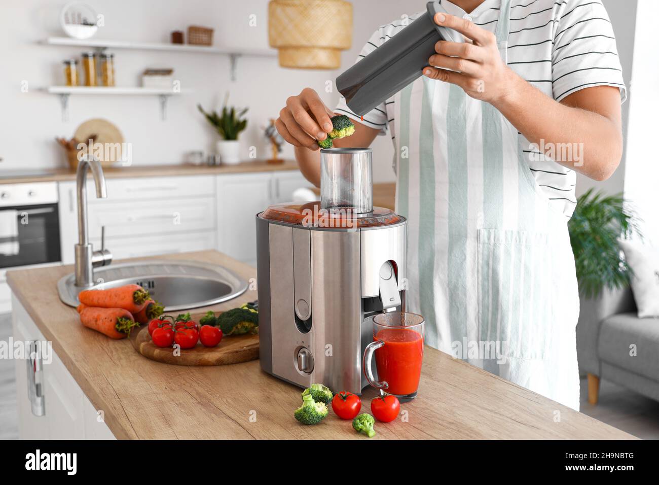 Junger Mann, der in der Küche gesunden Gemüsesaft zubereitet Stockfoto