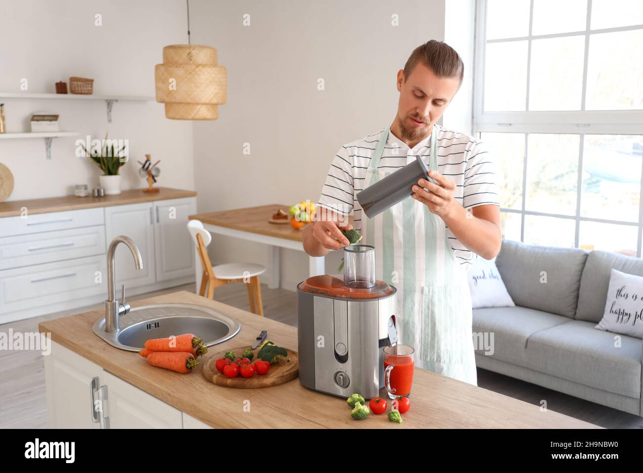 Junger Mann, der in der Küche gesunden Gemüsesaft zubereitet Stockfoto