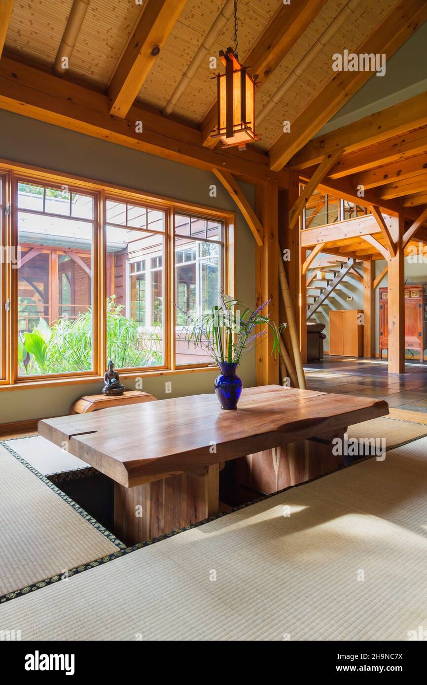 Lackierter Esstisch aus rustikalem Holz mit Tatami-Matten und einem kleinen indonesischen Teakholztisch im japanischen Esszimmer im Holzrahmen Stockfoto