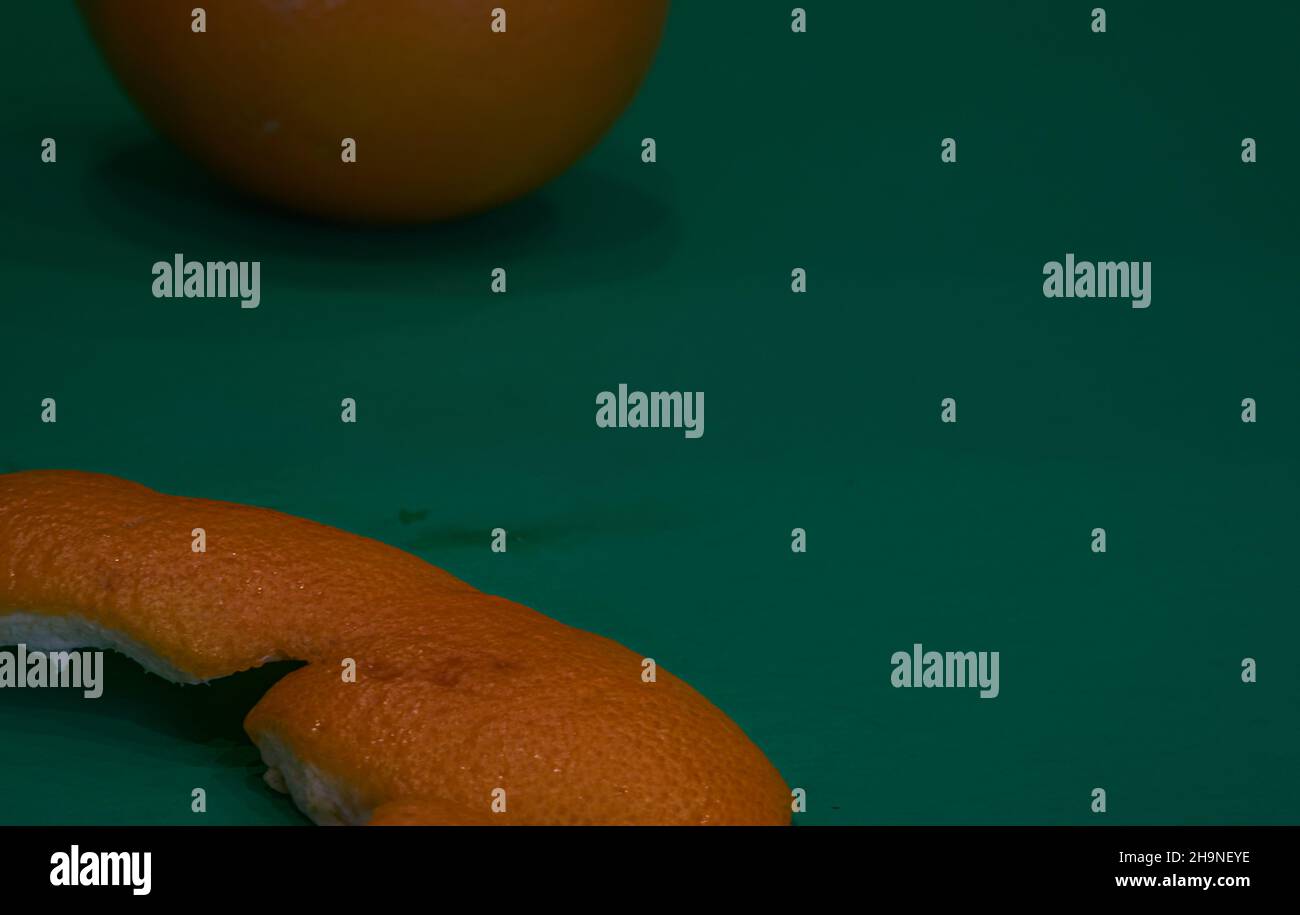 Eine Orangenschale auf grünem Hintergrund. Gut für einen Artikel über Orangen und Orangenprodukte. Stockfoto