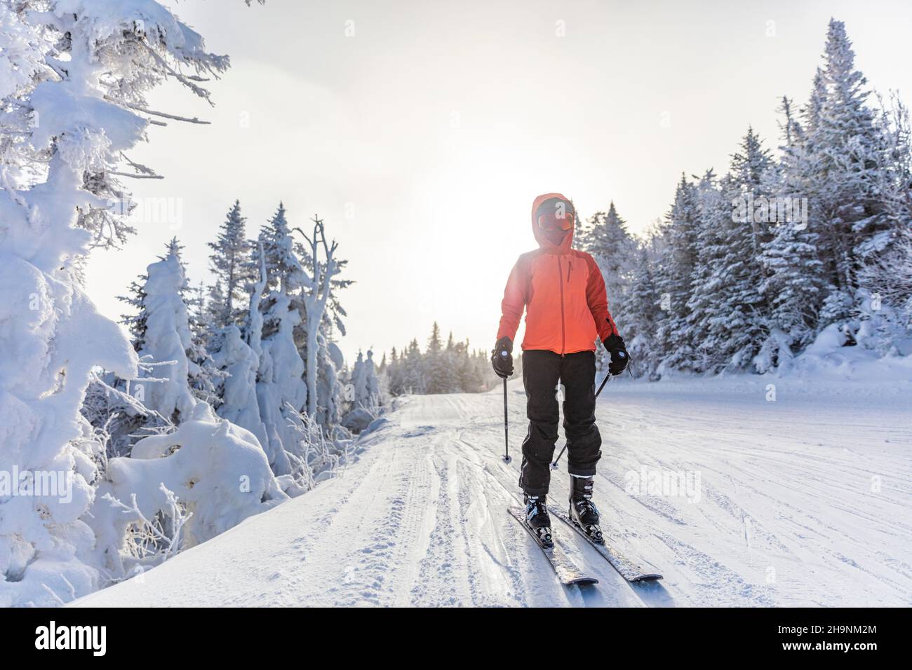 Skifahren Im Winter. Ski Frau Alpin Skifahrer gehen auf Skiern tragen Helm, coole Skibrille und Hardshell Winterjacke und Skihandschuhe. Frau geht bergab Stockfoto
