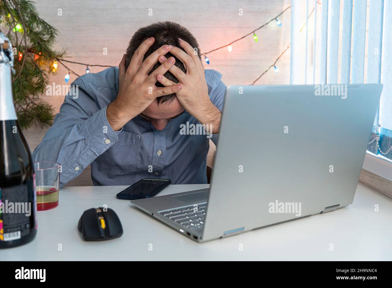 Junger Mann mit Kater nach der Neujahrsparty im Büro. Der Geschäftsmann ist bei der Arbeit müde. Ein betrunkener Mitarbeiter ist nach einer Firmenfeier krank Stockfoto