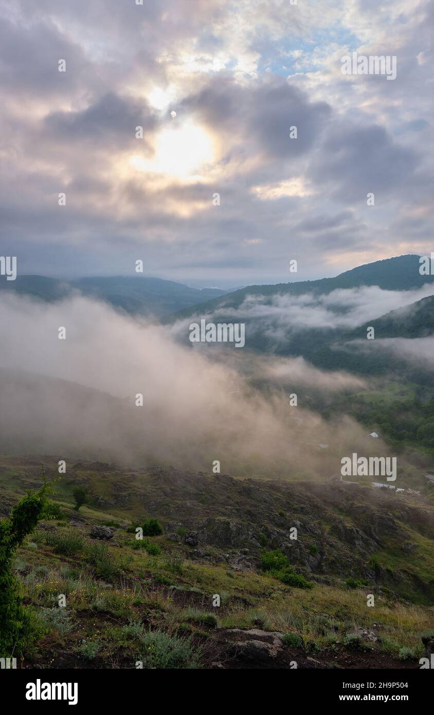 Steile Hochländer und Tiefebenen von Wäldern, Frühlingsblüten und ein Nebel mit der Sonne, die durch die Wolken Gosh Dorf, Armenien Stockfoto
