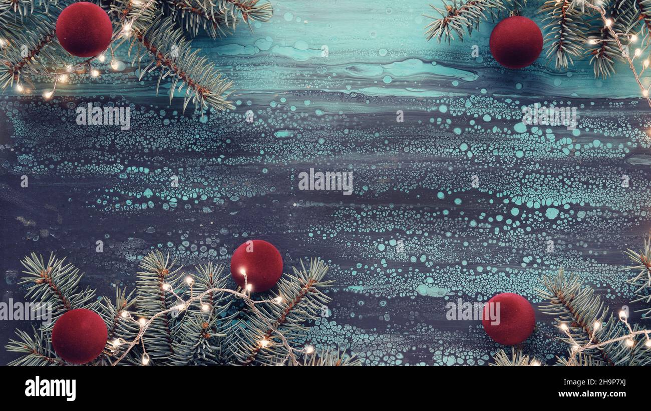 Silberner Weihnachtsrand mit Tannenzweigen, roten weichen flauschigen Bällen und exotischen Farnblättern und heller Girlande. Copy-Space, für Text platzieren. Acryl-Hintergrund Stockfoto