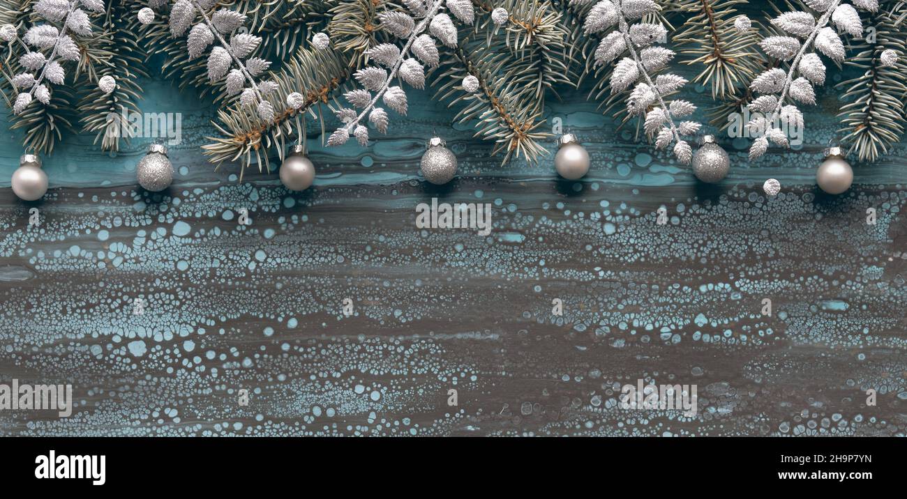 Silberner Weihnachtsrand mit Tannenzweigen, Glaskugeln und exotischen Farnblättern. Copy-Space, für Text platzieren. Flüssiger Acryl abstrakter Hintergrund in Stockfoto