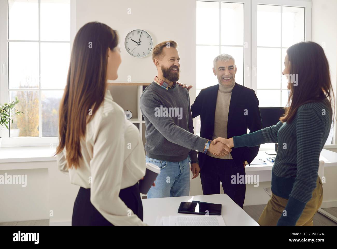 Glückliche, lächelnde Geschäftsleute treffen sich, machen Bekanntschaft und schütteln die Hände Stockfoto