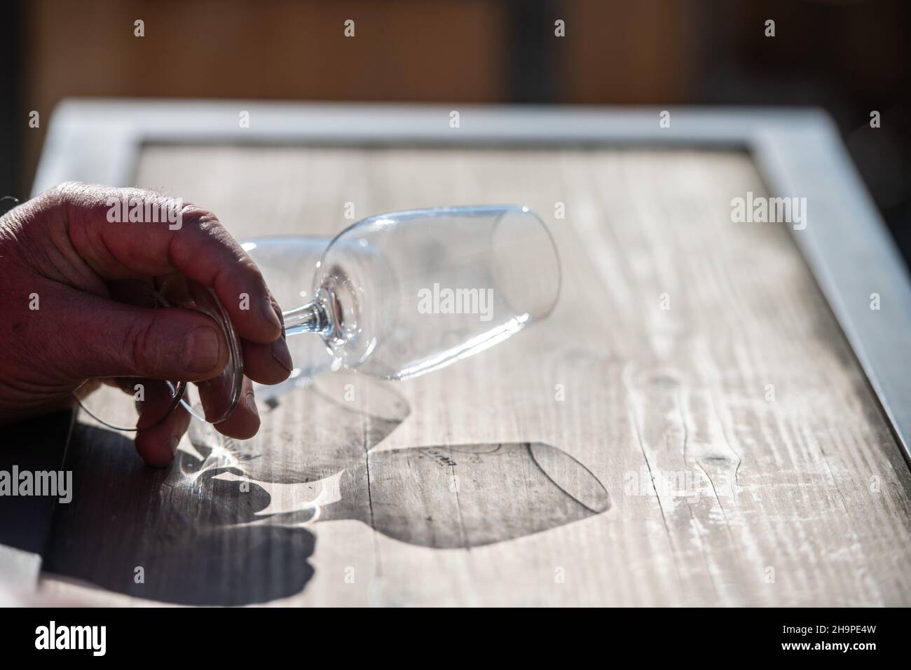 Hand eines älteren Mannes, der ein leeres Glas mit Stielstielung in der Hand hält und darauf wartet, dass jemand Wein hineingießt Stockfoto