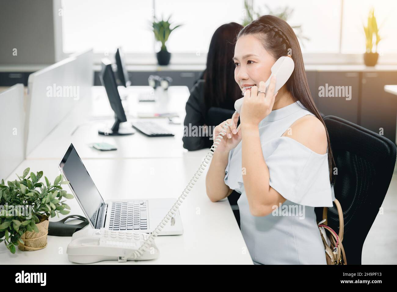 Geschäftsangestellter telefoniert, um den Kunden im Büro zu unterstützen, lächelt gerne. Stockfoto