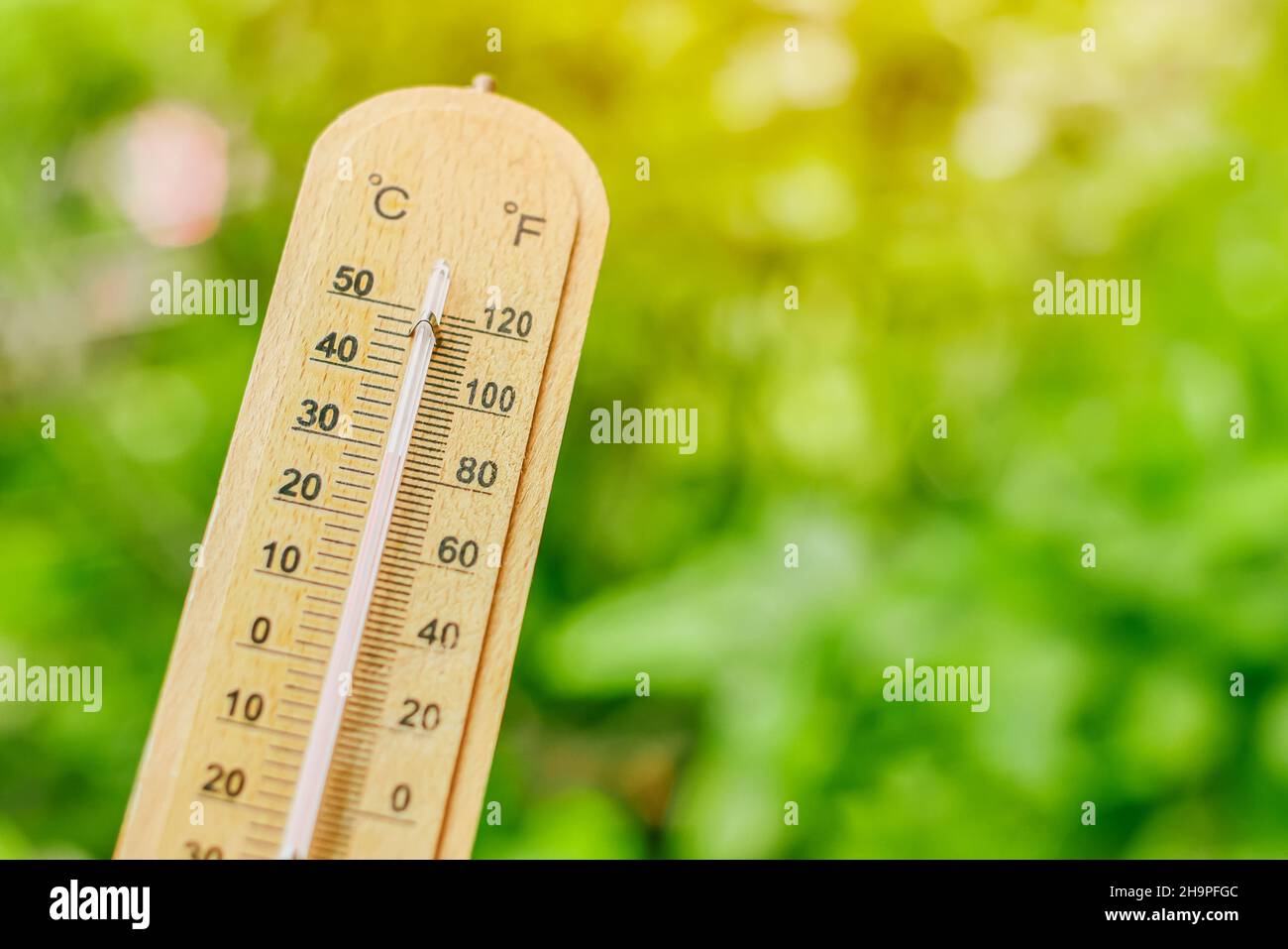 Thermometer mit verschwommenem grünen Hintergrund für kühlende Luft bei niedriger Temperatur aus dem Pflanzengarten Stockfoto