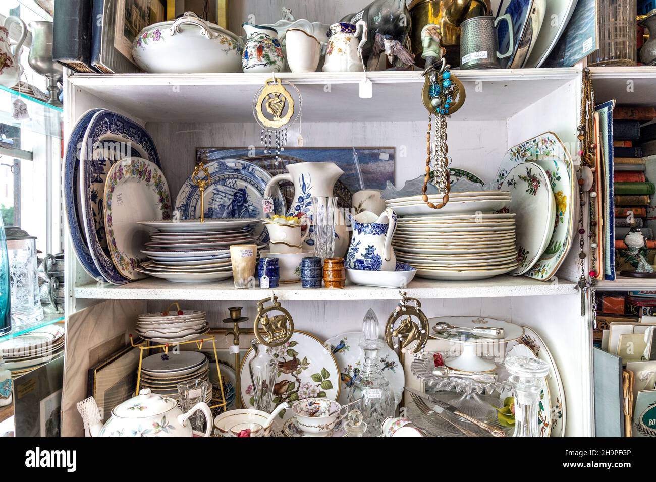 Regal mit einer Auswahl an Geschirr, Geschirr und Porzellan in einem Antiquitätengeschäft (Hampton Court Emporium, East Molesey, UK) Stockfoto