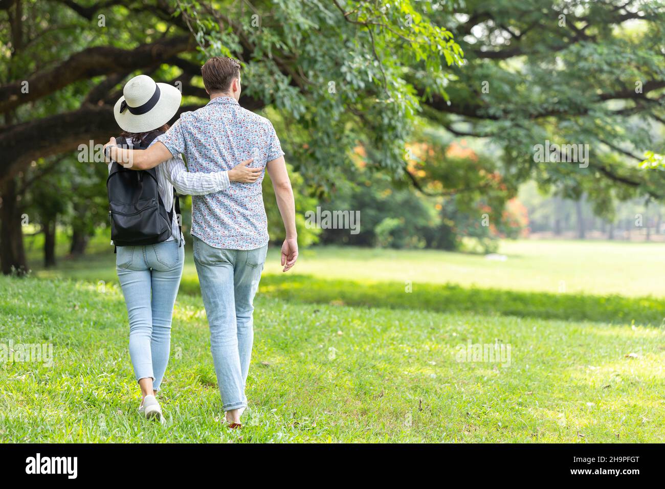 Paare, die im Freien spazieren gehen, umarmen sich gemeinsam auf der Grünfläche des Parks für Text Stockfoto