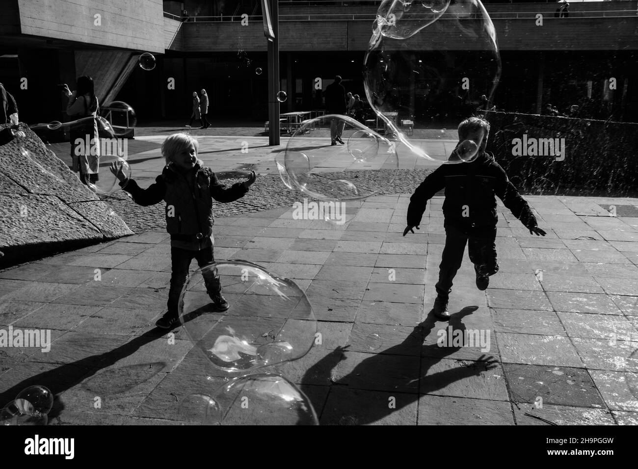 Kinder, die in den Straßen Londons mit großen Blasen spielen Stockfoto