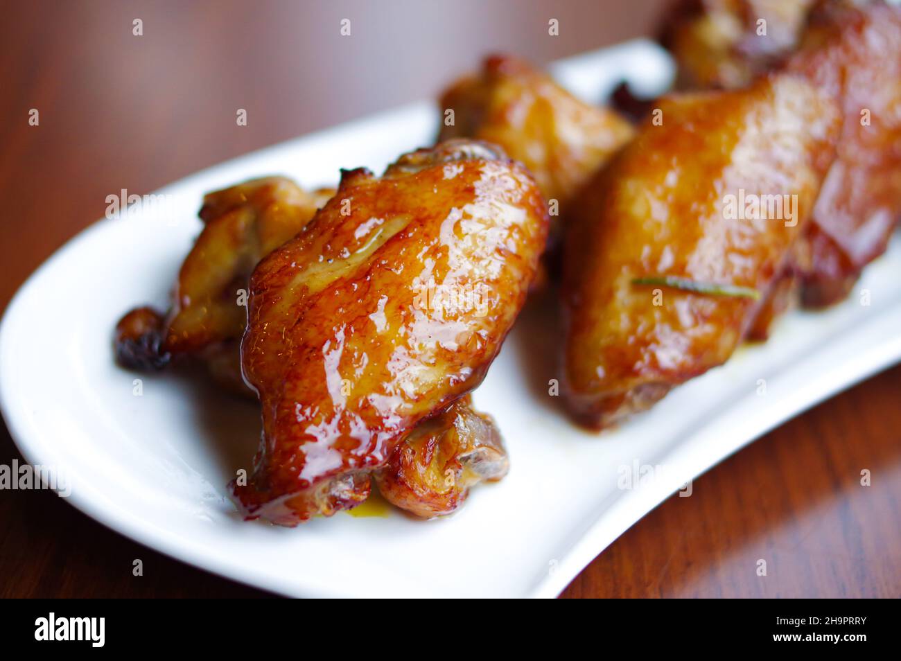 Gebackene Hähnchenflügel und Drumsticks auf weißem Teller Stockfoto