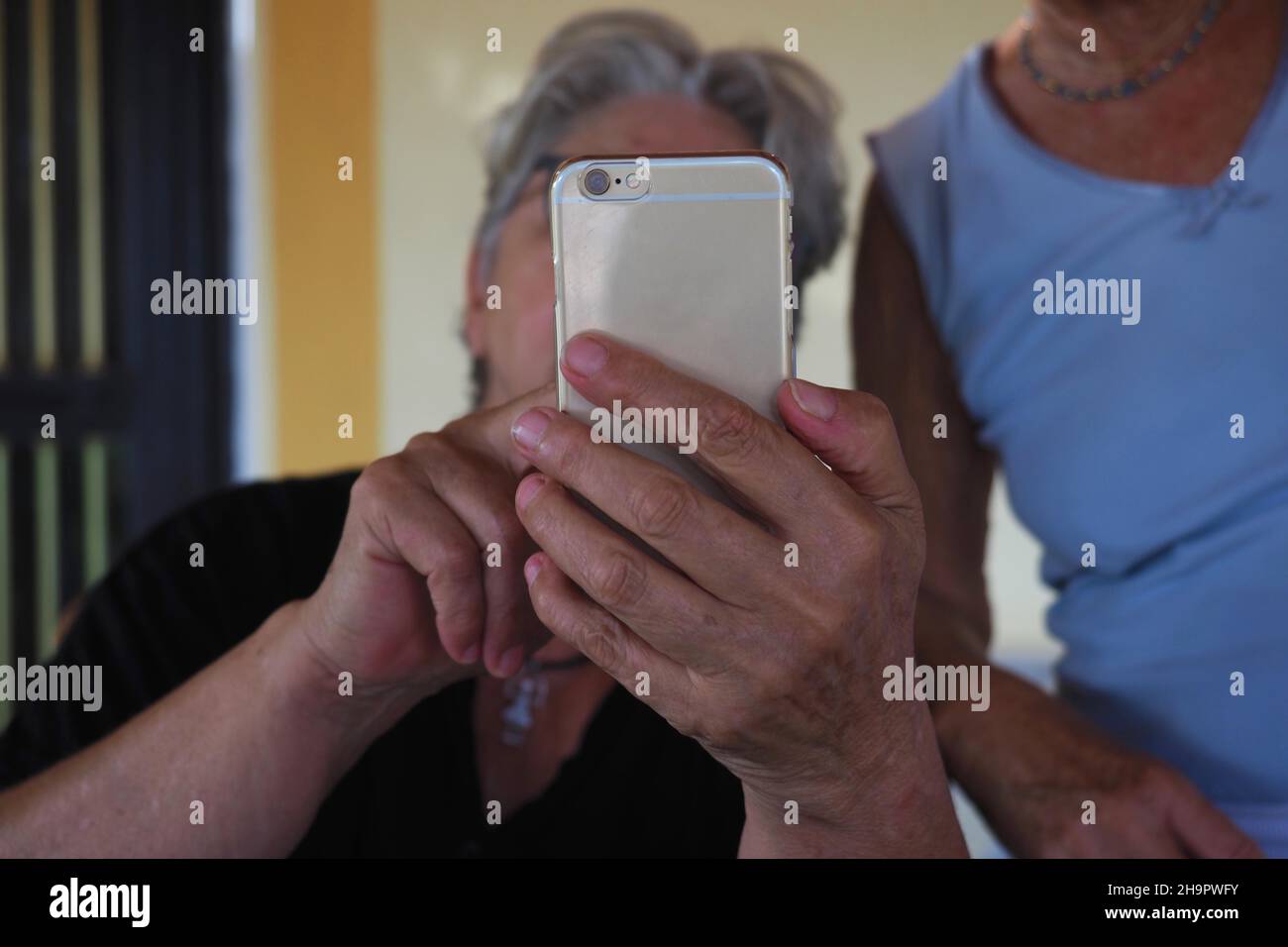 Zwei ältere Frauen helfen sich gegenseitig bei der Bedienung des Mobiltelefons, bei der Hilfe des Mobiltelefons, bei Alterungsproblemen, technischen Idioten, Technologieproblemen, Generierung Stockfoto