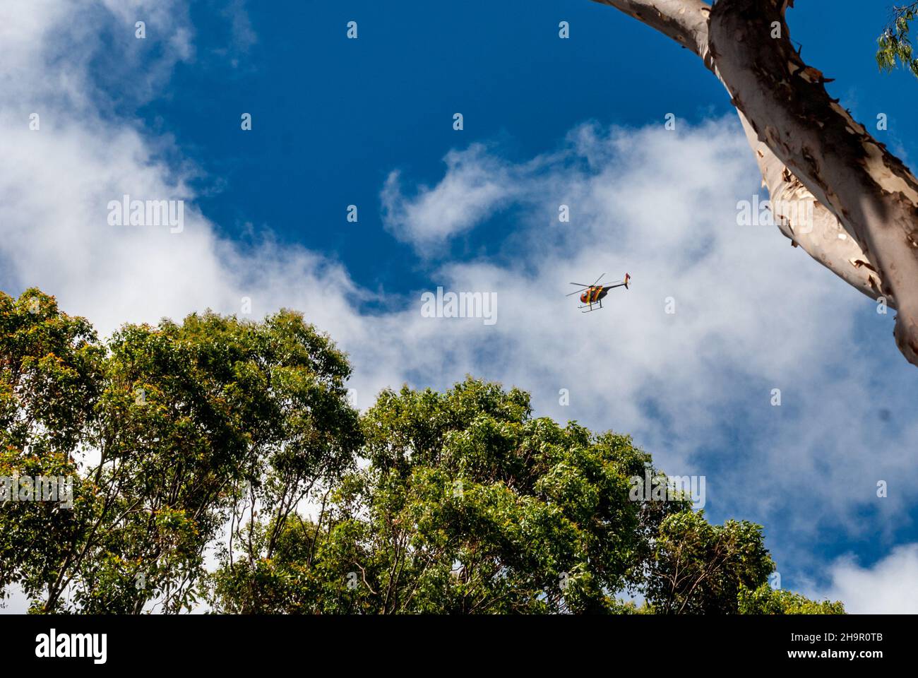 Honolulu, Hawaii - 02. Mai 2015: Mehrfarbiger Hubschrauber fliegt Touristen über Honolulu am blauen Himmel Stockfoto