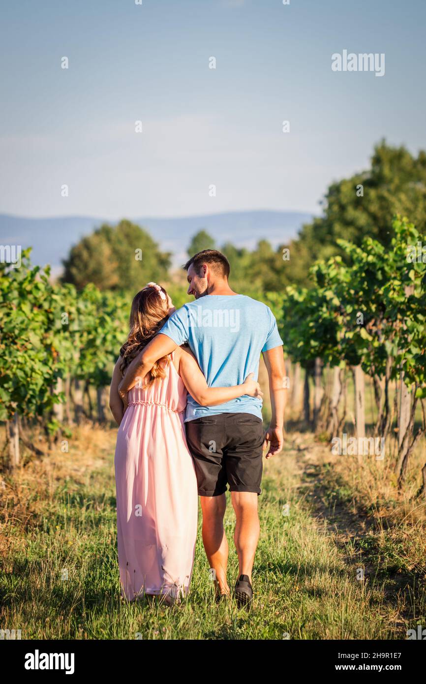 Glückliches Ehepaar, das gemeinsam im Freien unterwegs ist. Folge mir auf der Reise des Lebens. Junges Paar geht im Weinberg spazieren Stockfoto