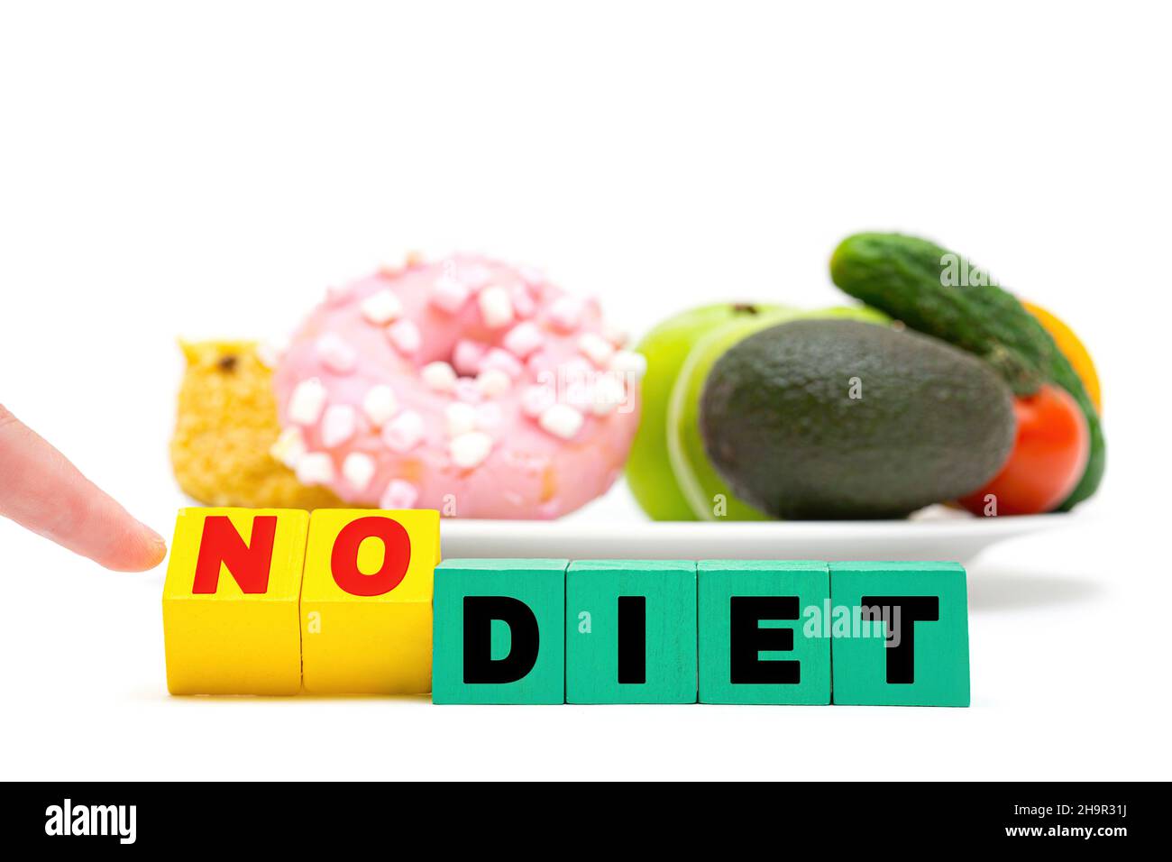 Text KEINE DIÄT aus farbigen Buchstabenblöcken vor einem weißen Teller mit Süßigkeiten, Obst und Gemüse. Treffen gesunder Lebensmittel. Stockfoto