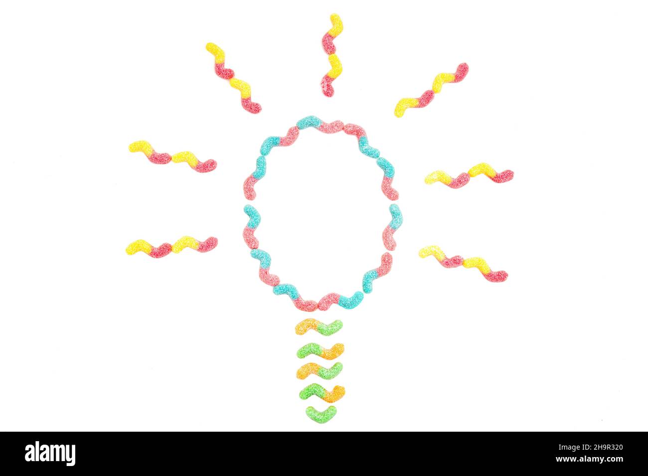 Glühbirne Symbol aus bunten Zucker überzogen Gummiwürmer auf weiß isoliert. Zucker hilft beim Denken. Stockfoto