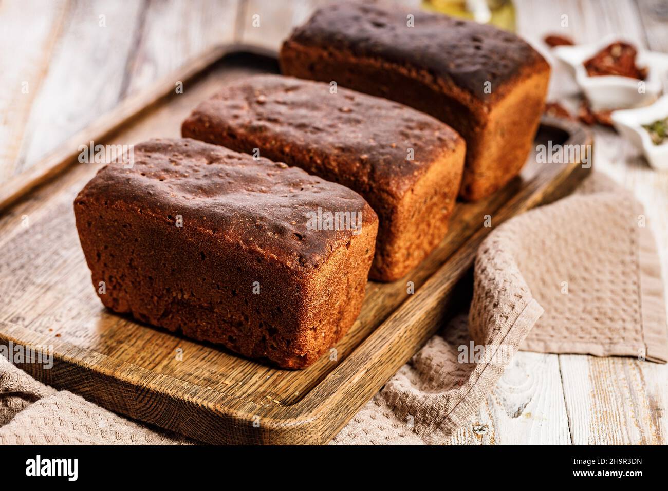 Bio-Roggenbrotlafs. Frisches Brot aus Vollkorn-Roggenmehl. Hausgemachtes köstliches Gebäck auf einem Holztablett auf einem rustikalen Hintergrund. Nahaufnahme. C Stockfoto