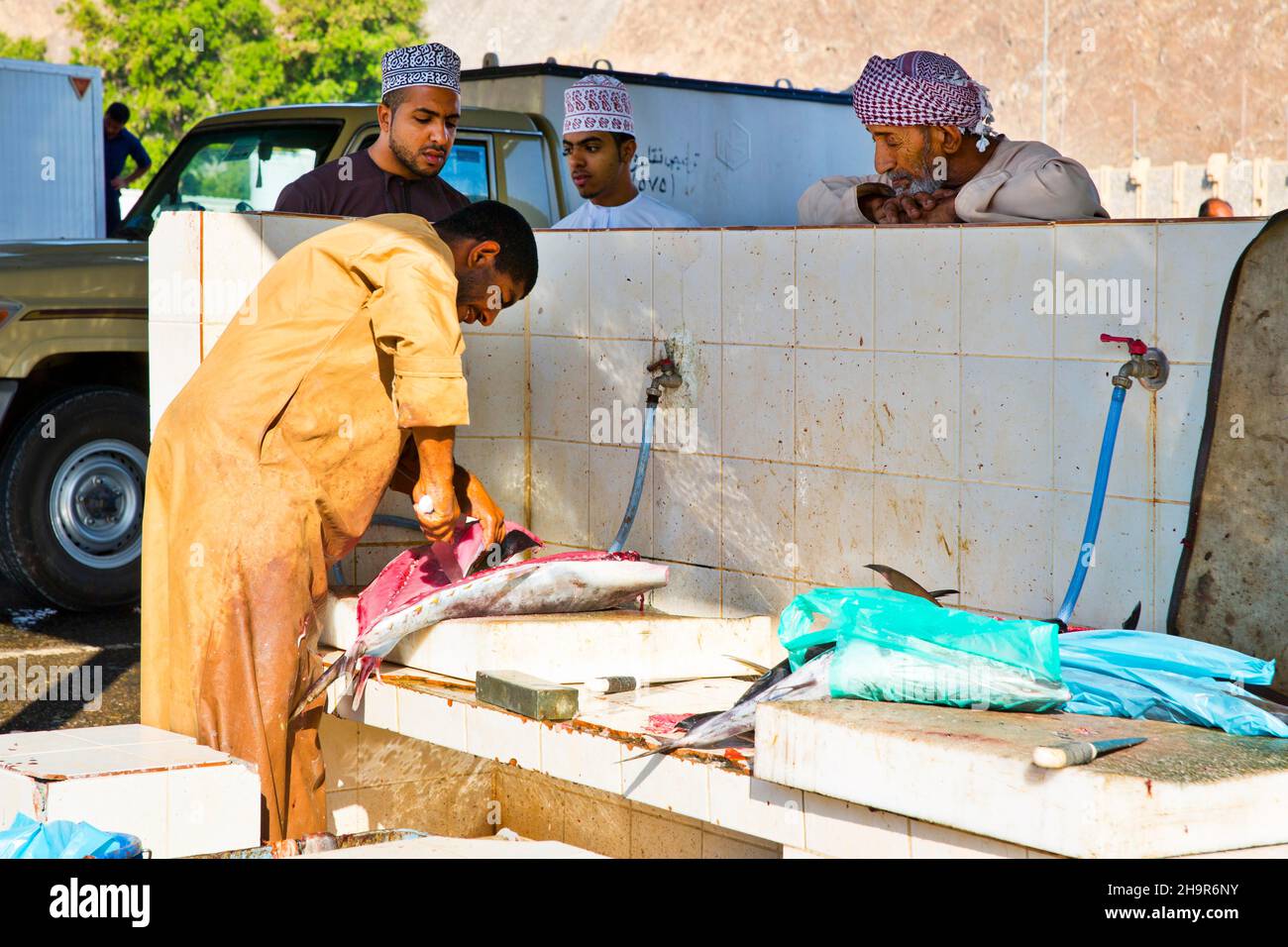 Der Mensch entkalkt Fische für Bargeld und verarbeitet sie in praktischen Einheiten mit großen Spaltmaschinen, Mutrah-Fischmarkt, Muscat, Oman Stockfoto