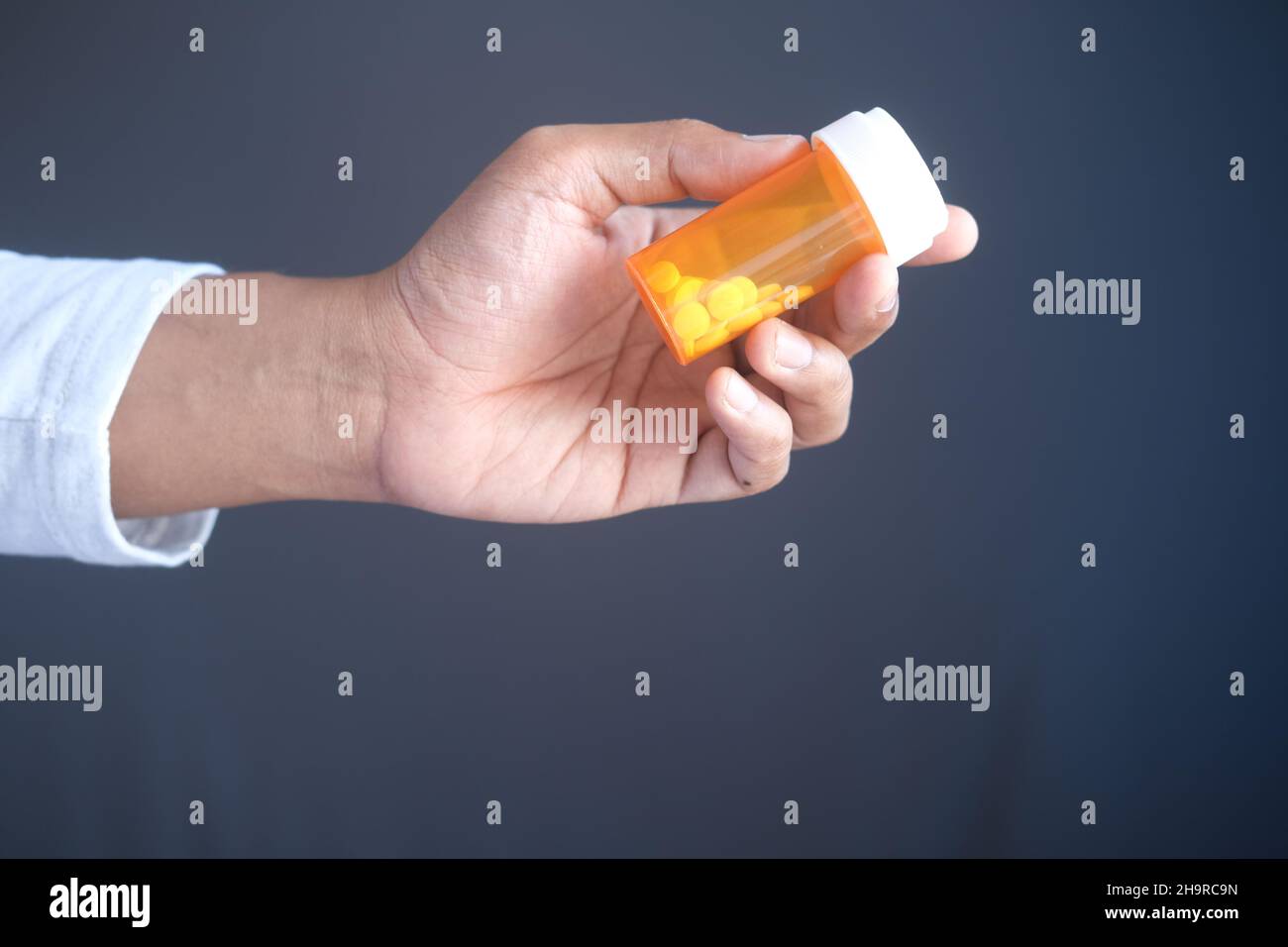 Junger Mann hält einen Behälter mit Medikamentenpillen in der Hand Stockfoto