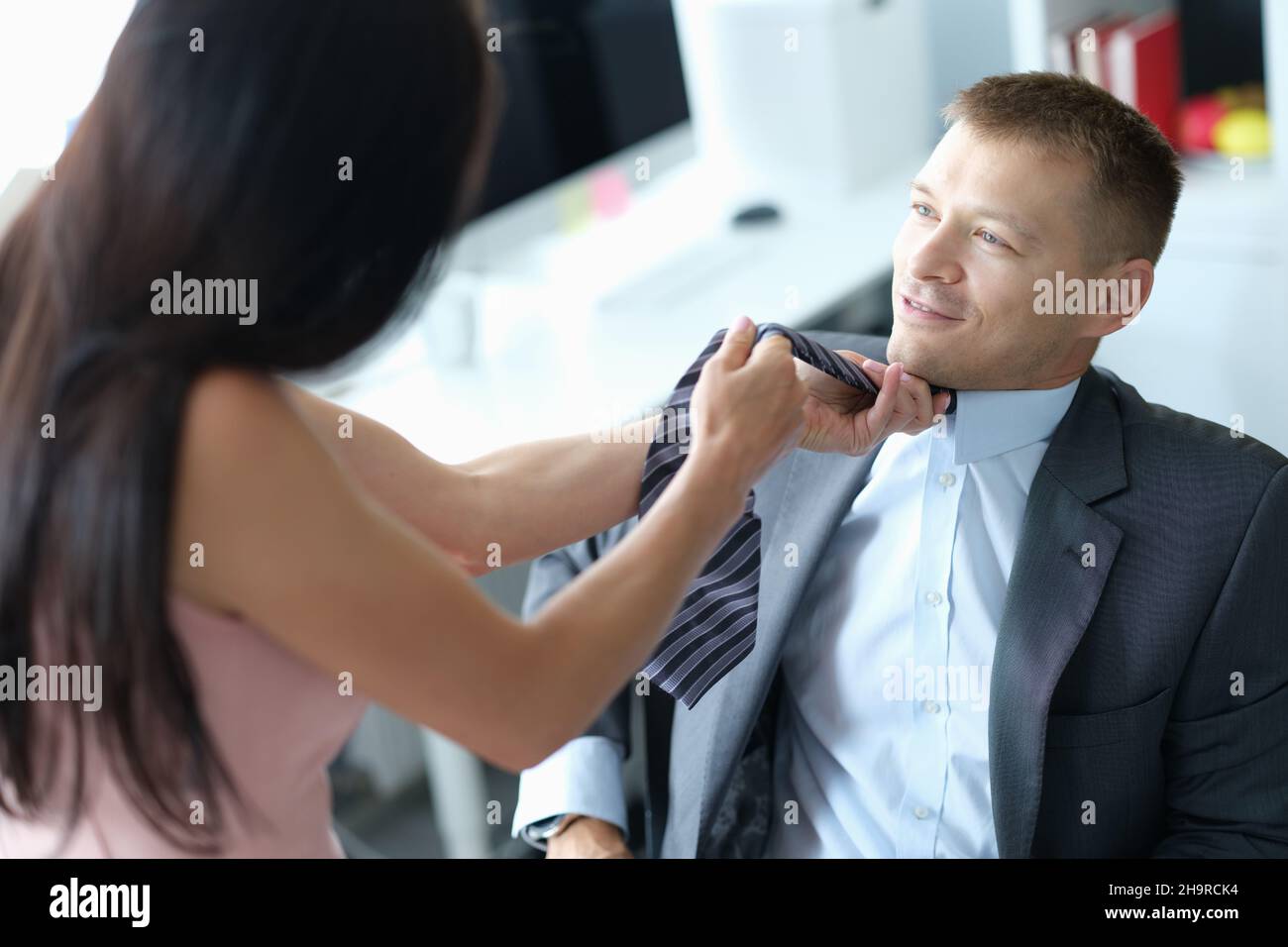 Weibliche Vorgesetzte zieht Krawatte von jungen Angestellten Stockfoto