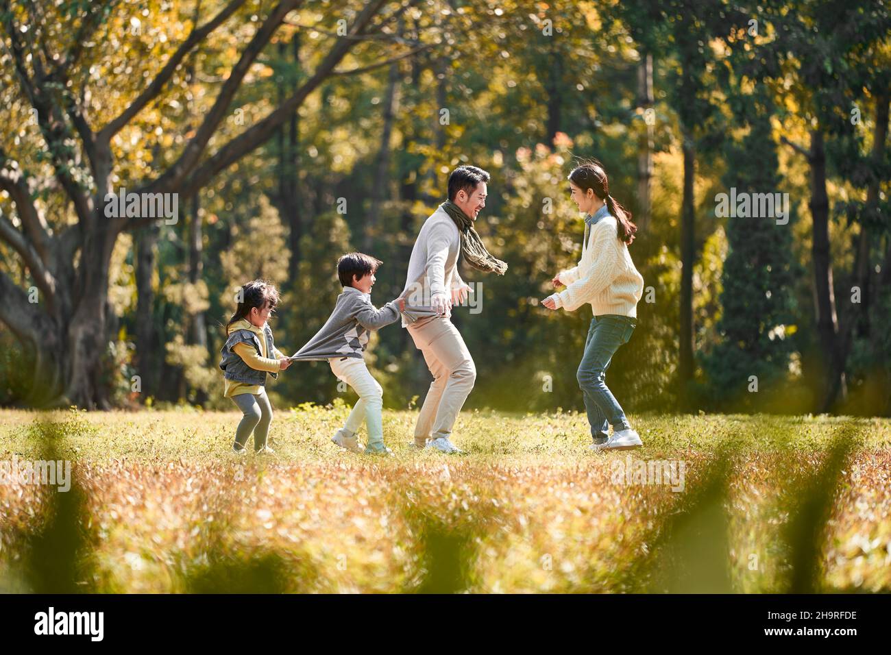 Junge asiatische Familie mit zwei Kindern, die Spaß beim Spielen im Freien im Park haben Stockfoto