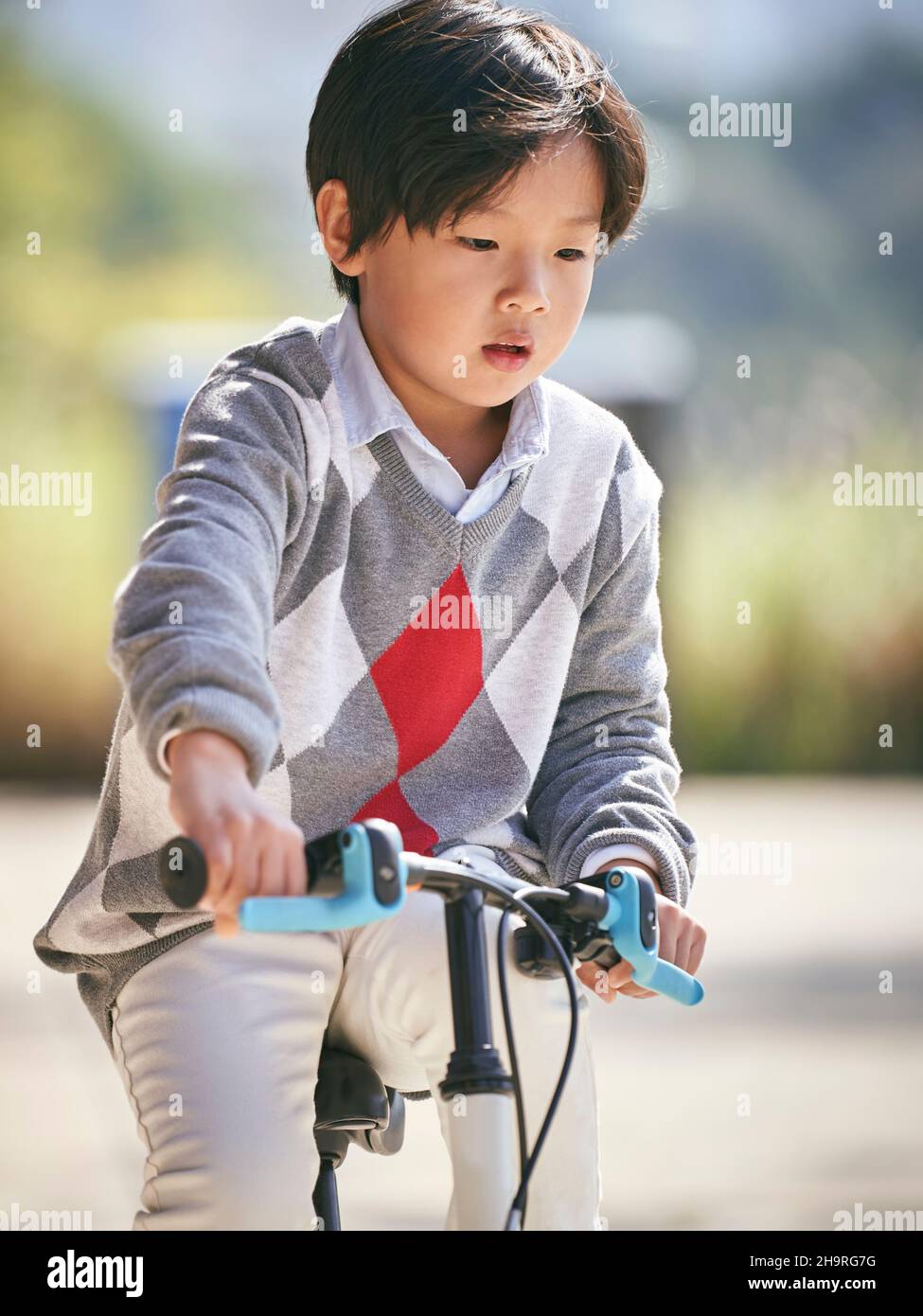 Fünf Jahre alter asiatischer kleiner Junge, der im Freien Fahrrad fährt Stockfoto