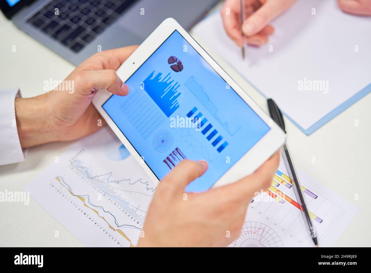 Hände des Geschäftsmannes halten Tablet-Computer mit Grafiken und Diagramme Stockfoto