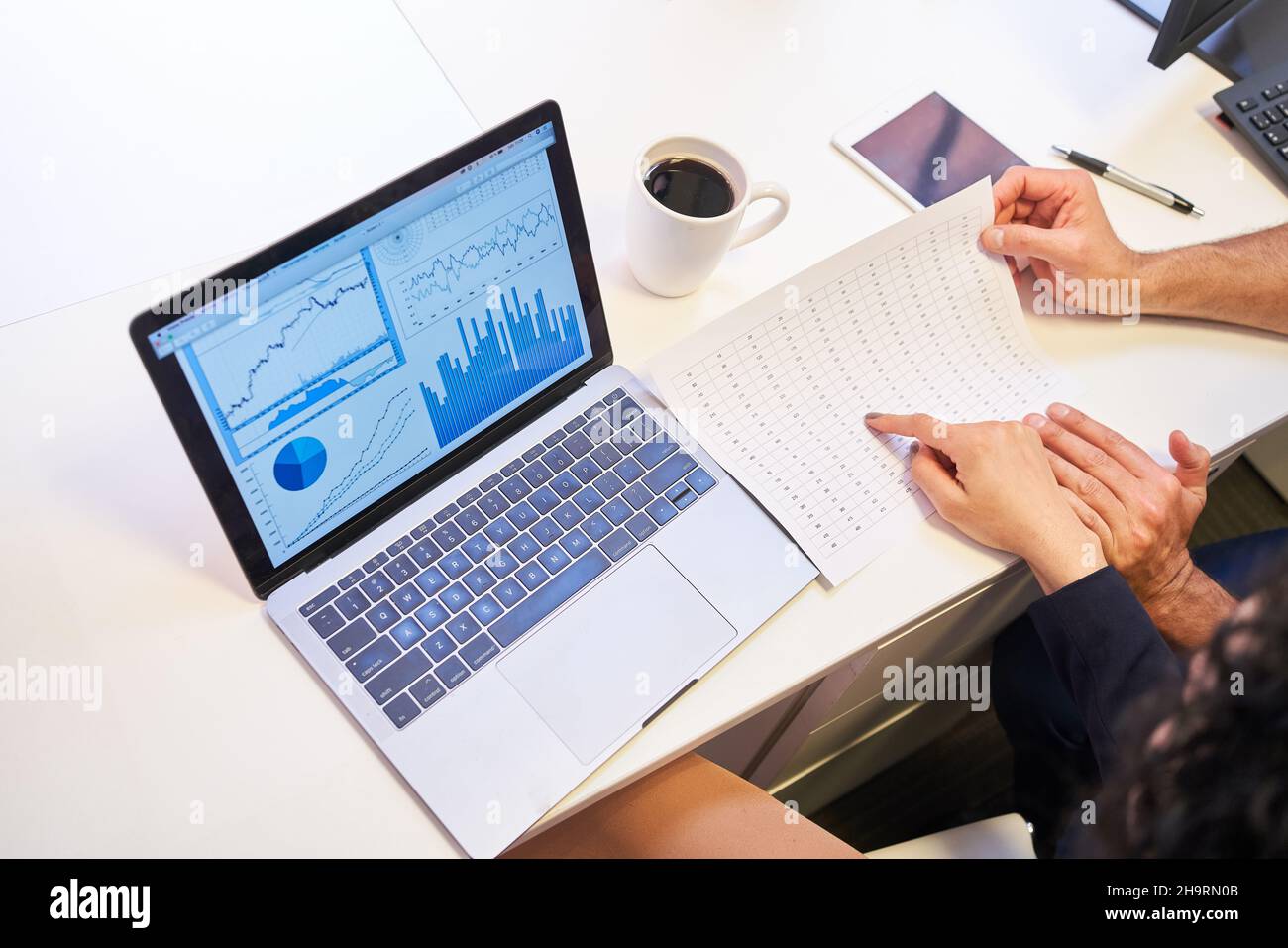 Laptop-Computer auf dem Schreibtisch mit Diagrammen und Grafiken für die Finanzanalyse Stockfoto