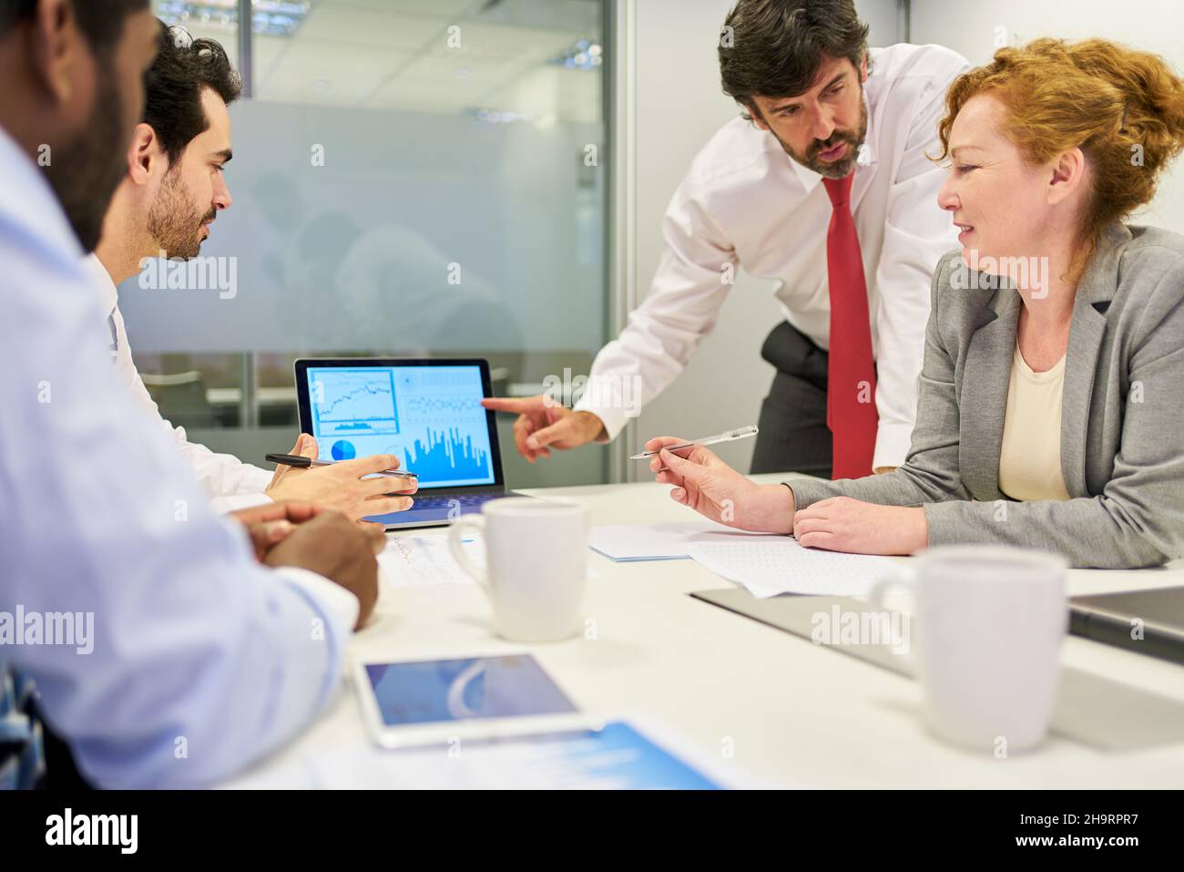 Geschäftsteam und Berater diskutieren Finanzen und Strategie am Computer Stockfoto