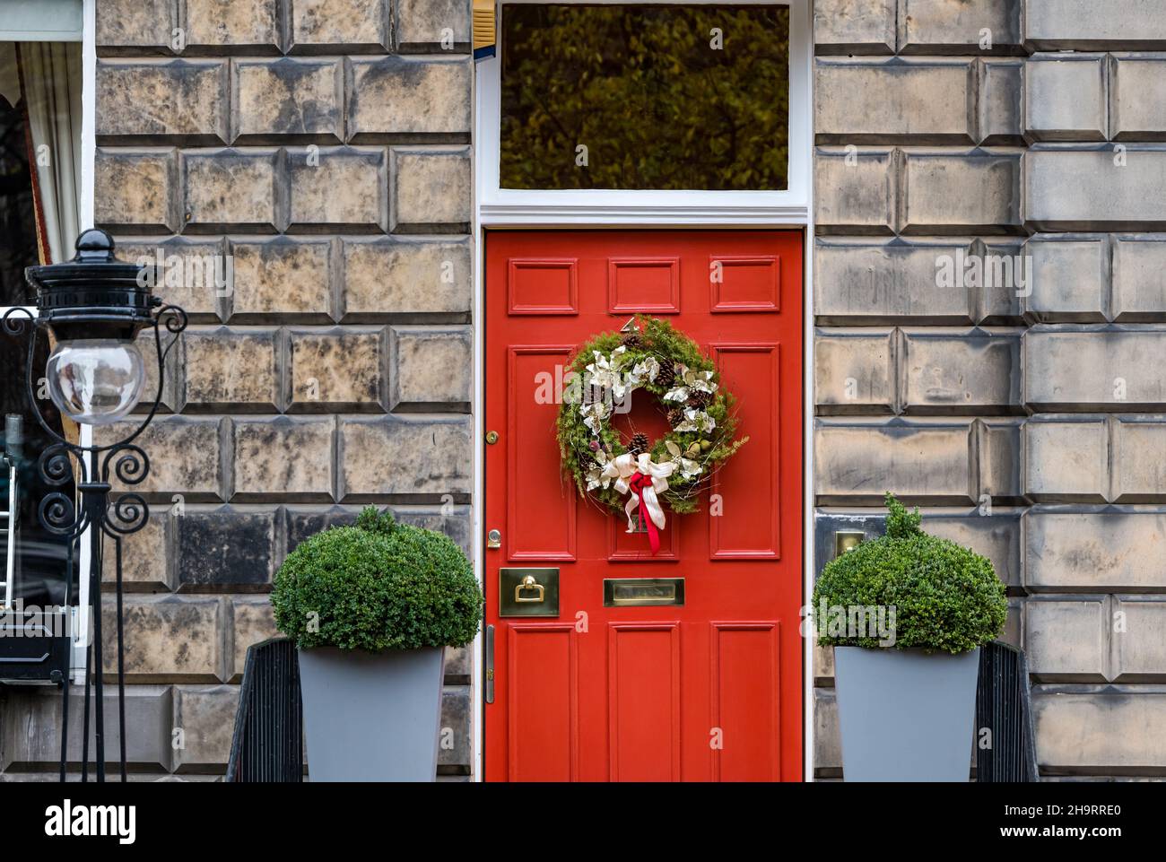 Georgianisches Stadthaus, rot bemalte Eingangstür mit Weihnachtskranz und altem Lampenposten, Edinburgh New Town, Schottland, Großbritannien Stockfoto
